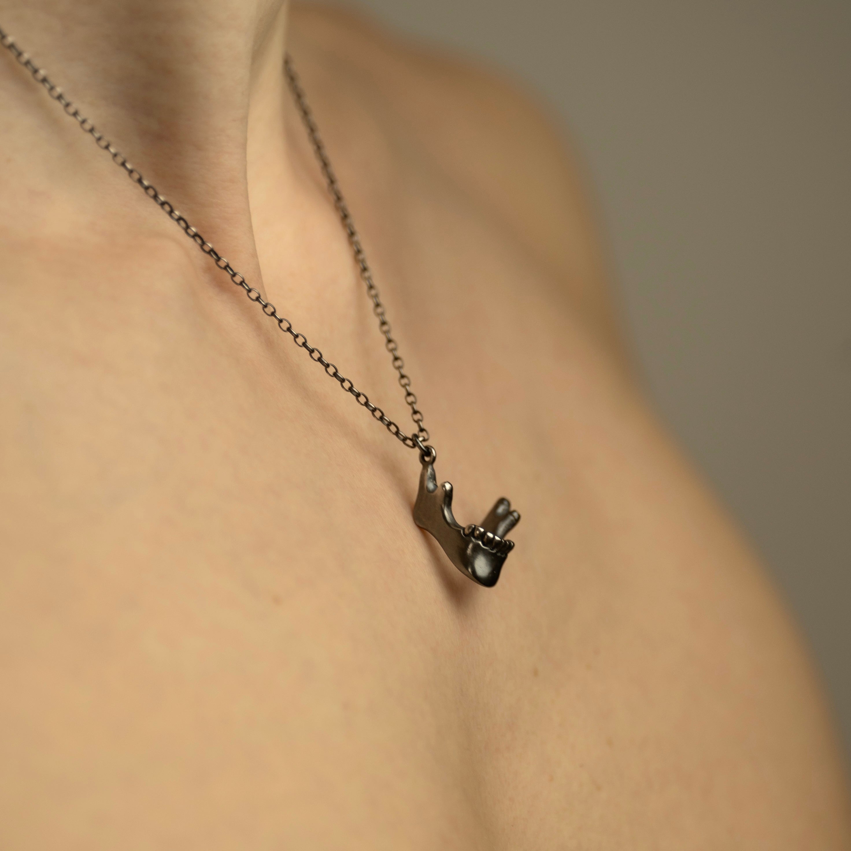 Silver Skull Jaw miniature charm handcrafted in solid sterling by Macabre Gadgets - close up of the jewelry piece on a female model