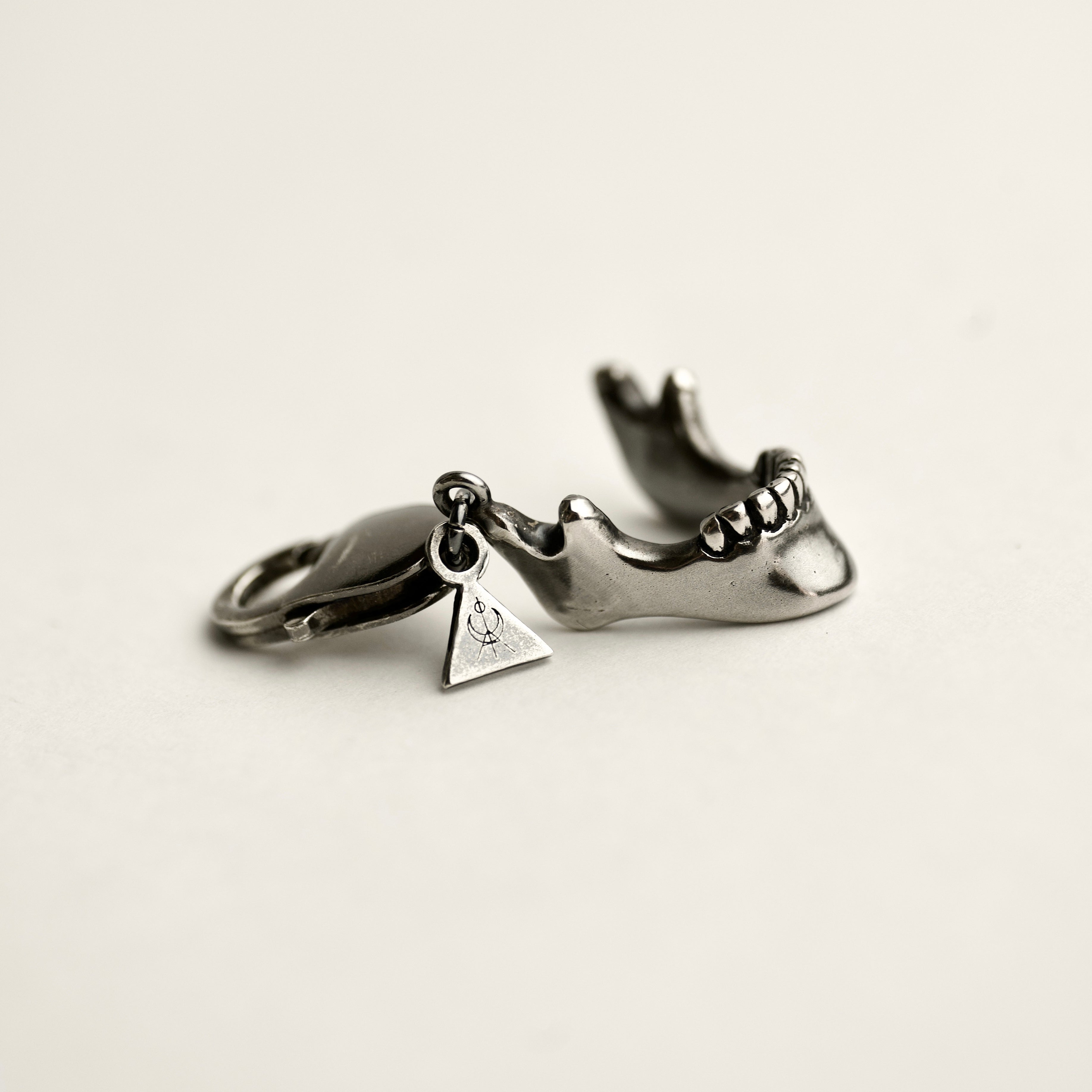 Silver Skull Jaw miniature charm handcrafted by Macabre Gadgets on a lobster lock - lying on a white background - perfect wallet or a handbag accessory