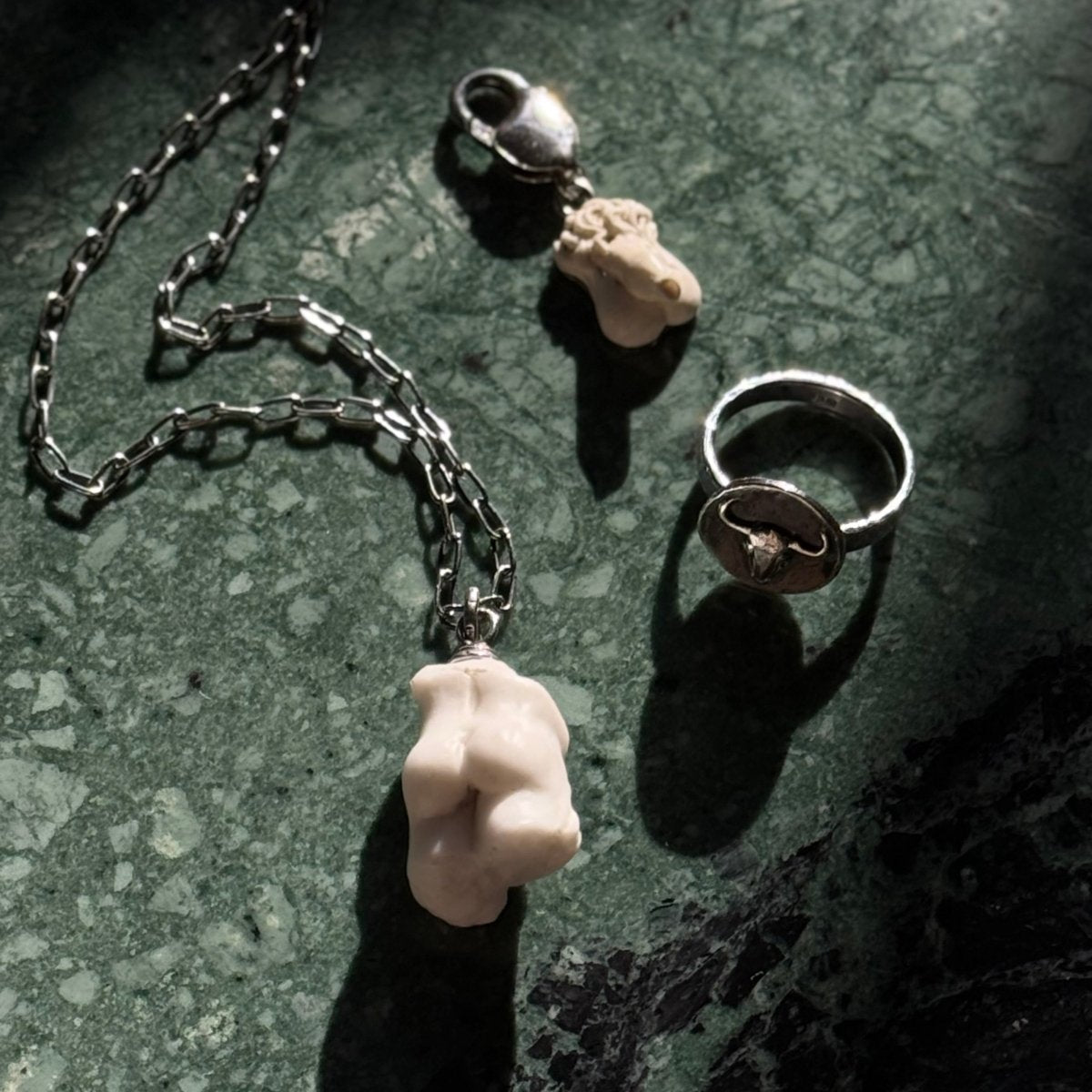 Bull Ancient Coin ring, Male Torso pendant  and Phallus charm by Macabre Gadgets on green marble surface - mythology inspired jewelry lifestyle shot