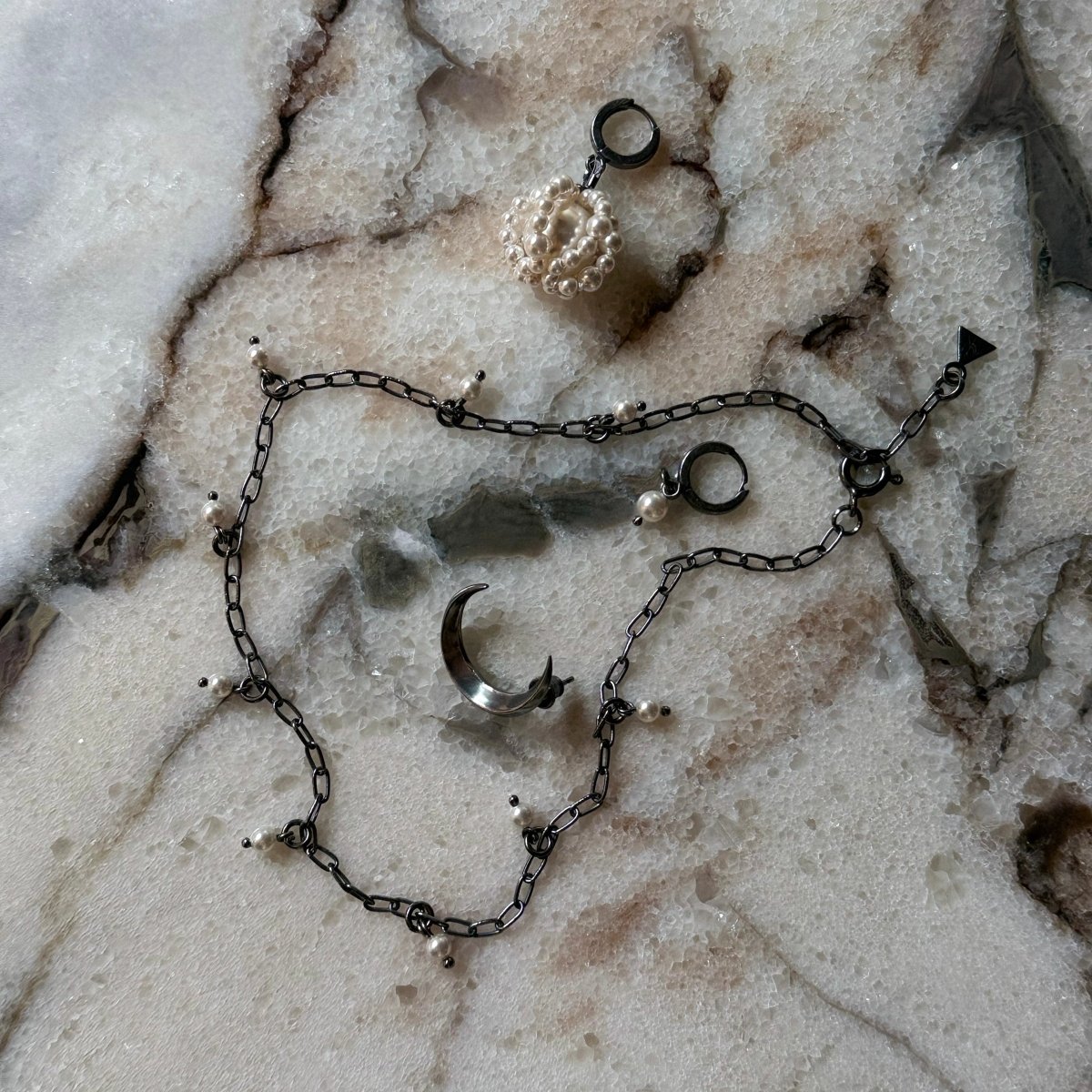 Luna earring, Pearl Cloud earring and Ancient Pearl necklace by Macabre Gadgets on a marble surface