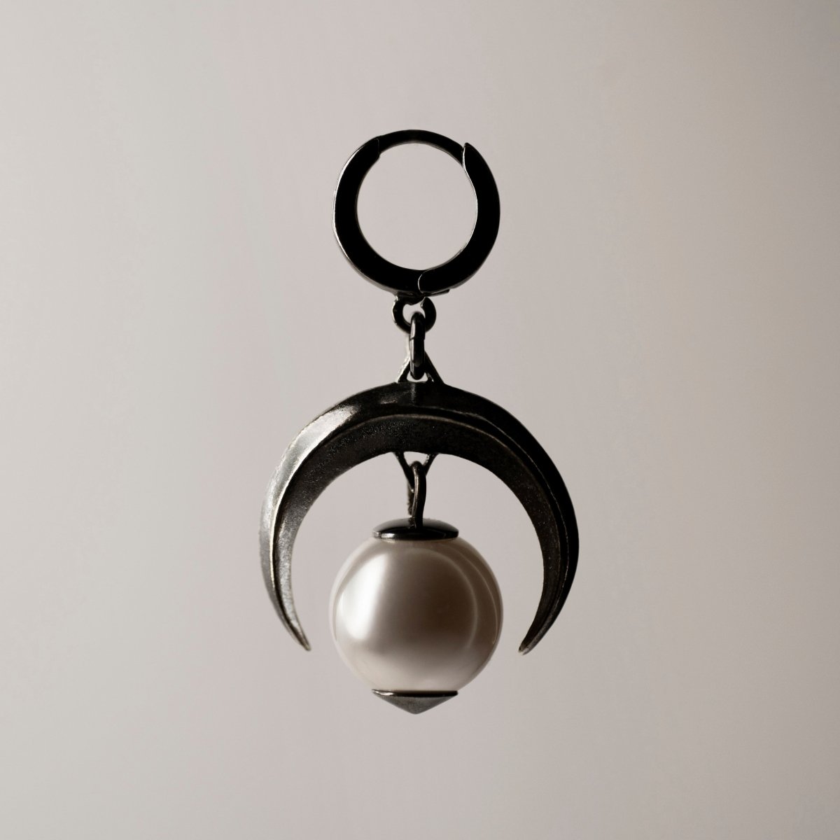 Moon earring - silver crescent moon-shaped earring with large pearl on neutral background