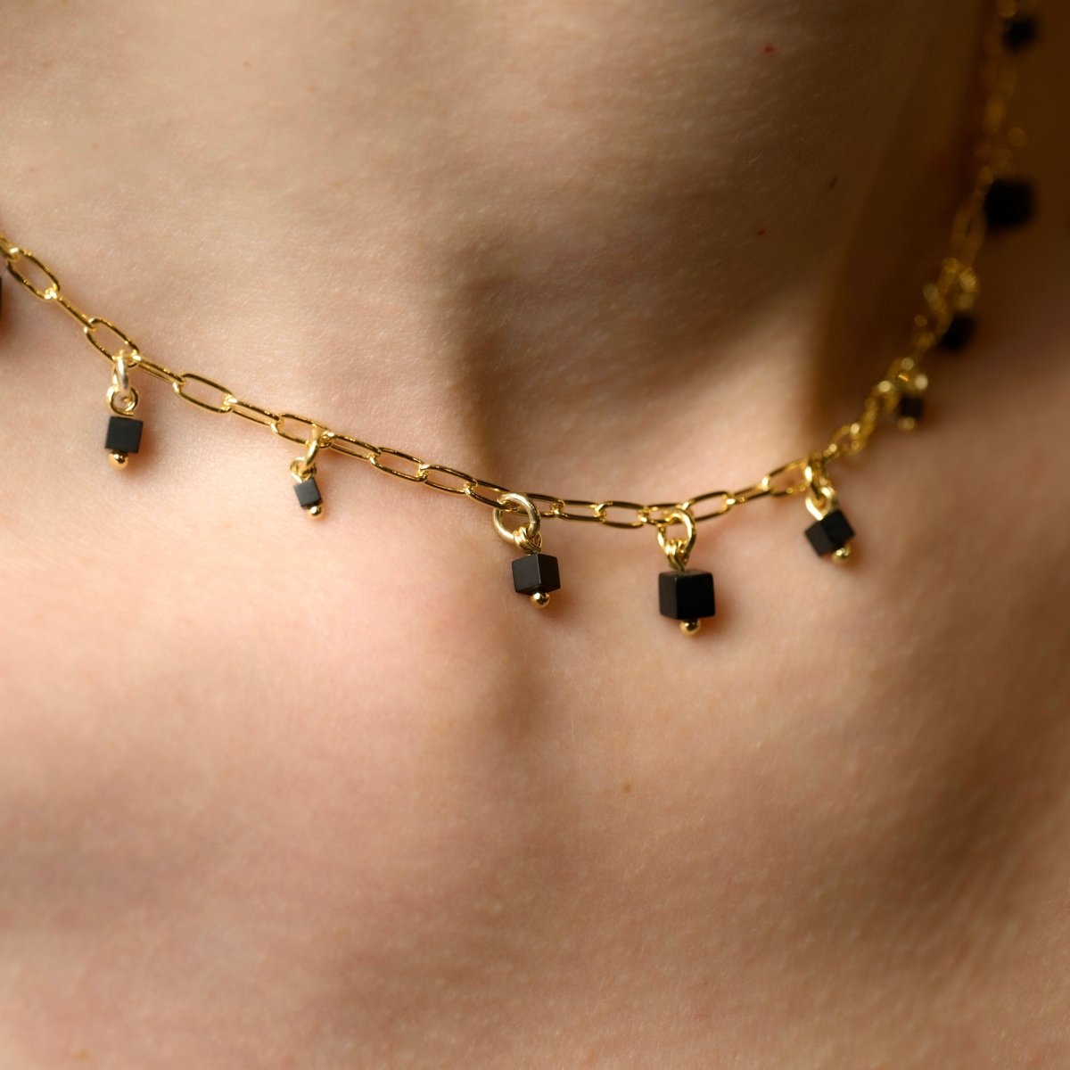 Mosaic necklace - close-up of link necklace with square black beads on woman's neckk