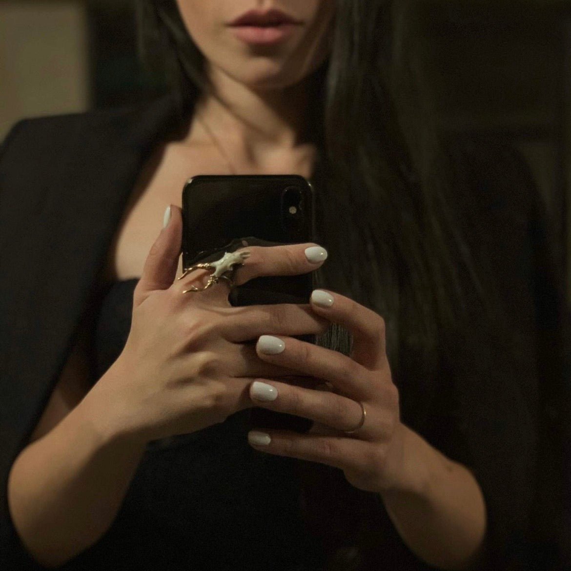 Doe Skull ring on a woman's hand with the smartphone, the woman is taking a selfie in the mirror