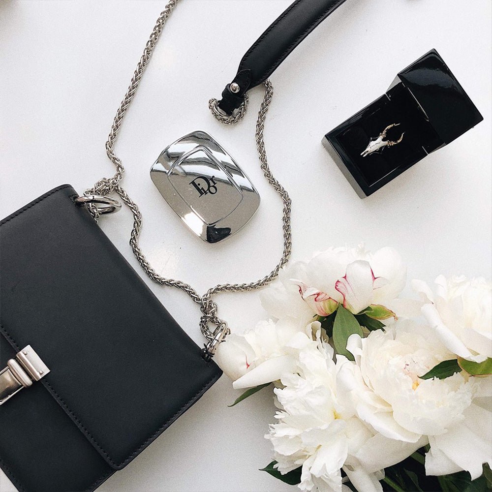 Doe Skull ring in a jewelry box on a white surface with perfume bottle, a handbag and a flower, lifestyle editorial