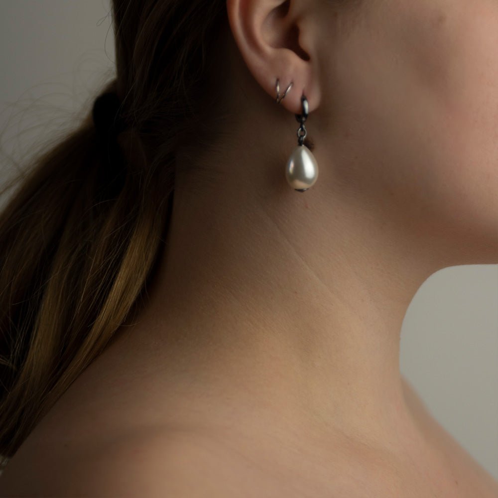 Large pearl earring on a female plus size model with a long ponytail