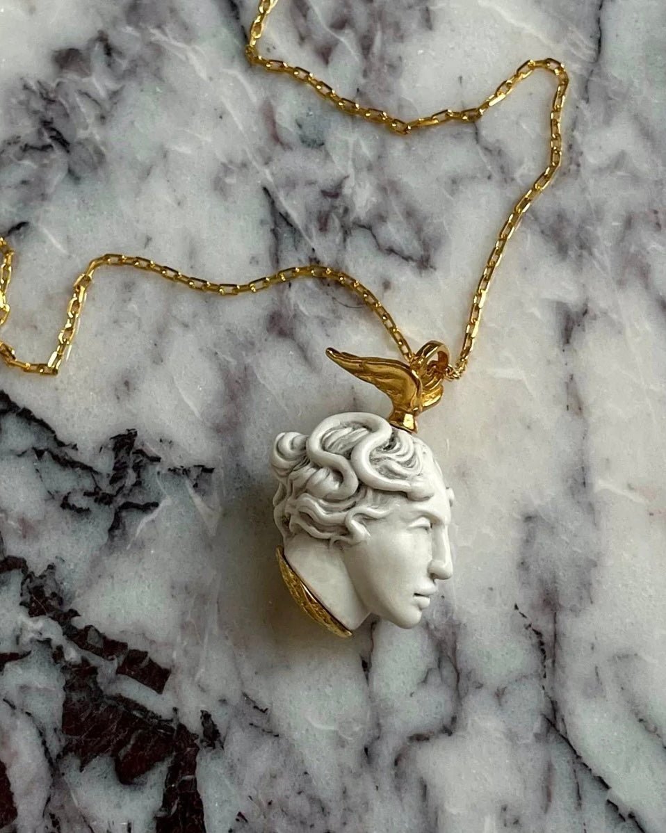 Medusa pendant on white marble surface, mythology necklace lifestyle shot