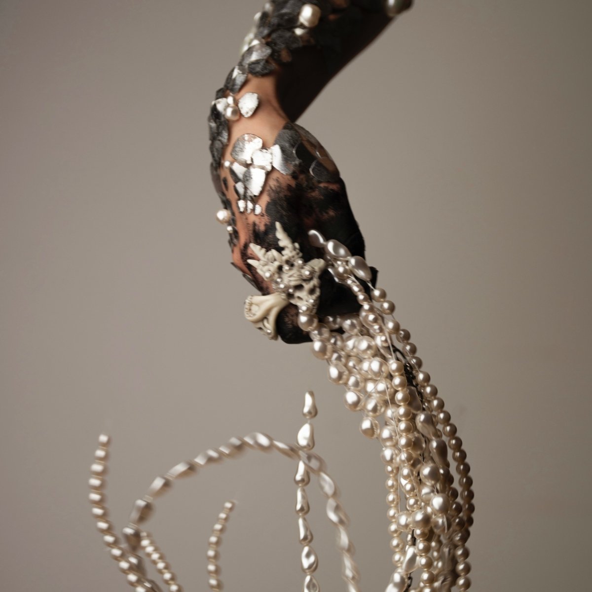Octopus Skull ring featured in a "Siren" campaign on a hand covered with silver scales with handful of pearls