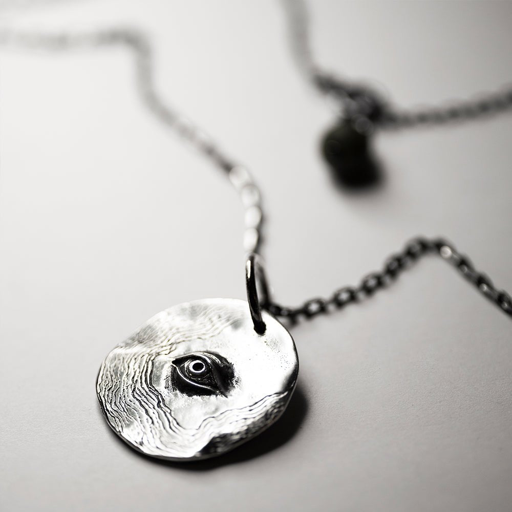 Silver Eye Pendant - textured silver charm on white background