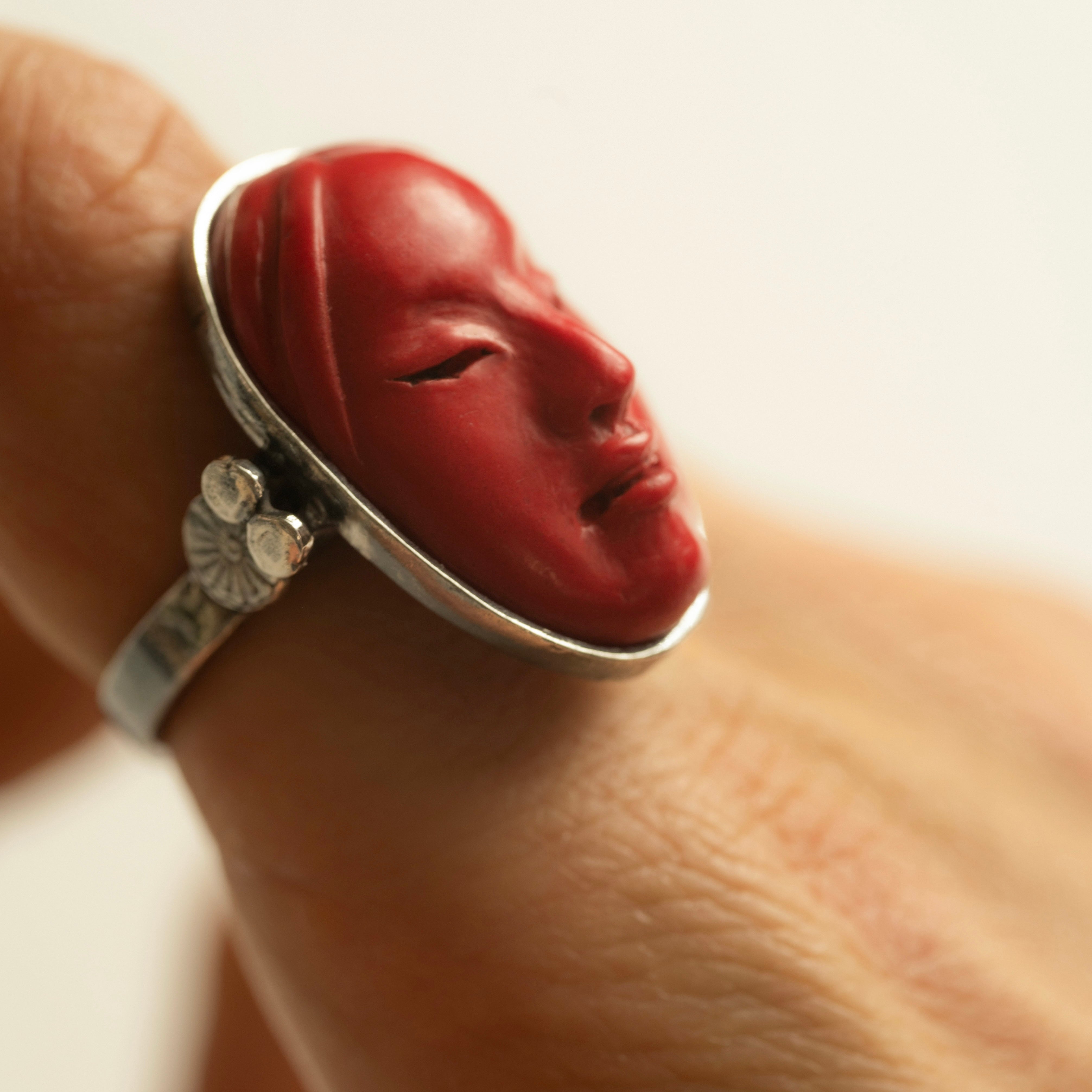 Mask ring - red variant - closeup on hand, index finger, showing hand sculpting details of the ring