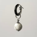 Silver hoop earring with a marbled stone pendant on a light gray background