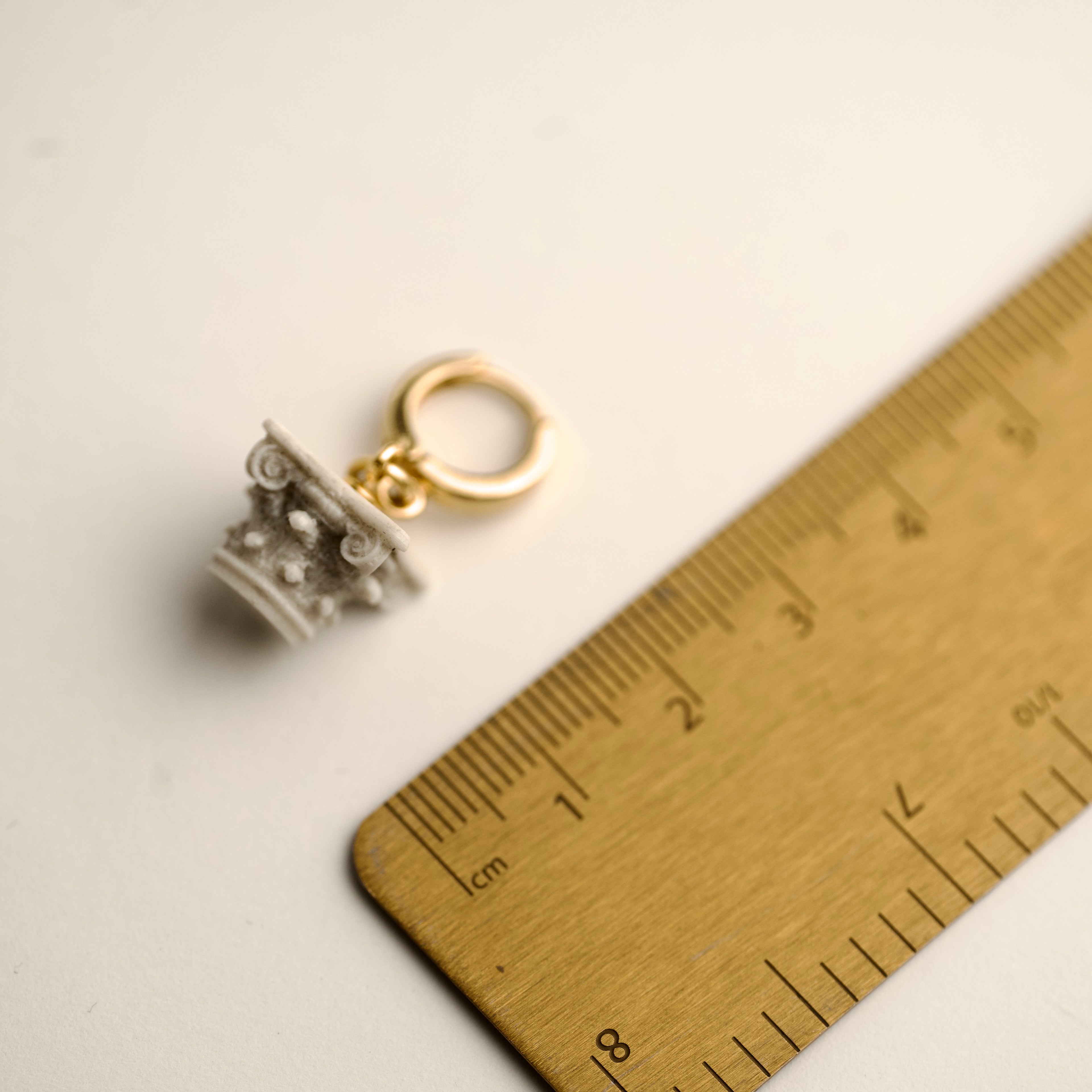 Miniature corinth colimn top on 24k gold plated hoop - architecture inspired earring next to the brass ruller to demonstrate dimensions