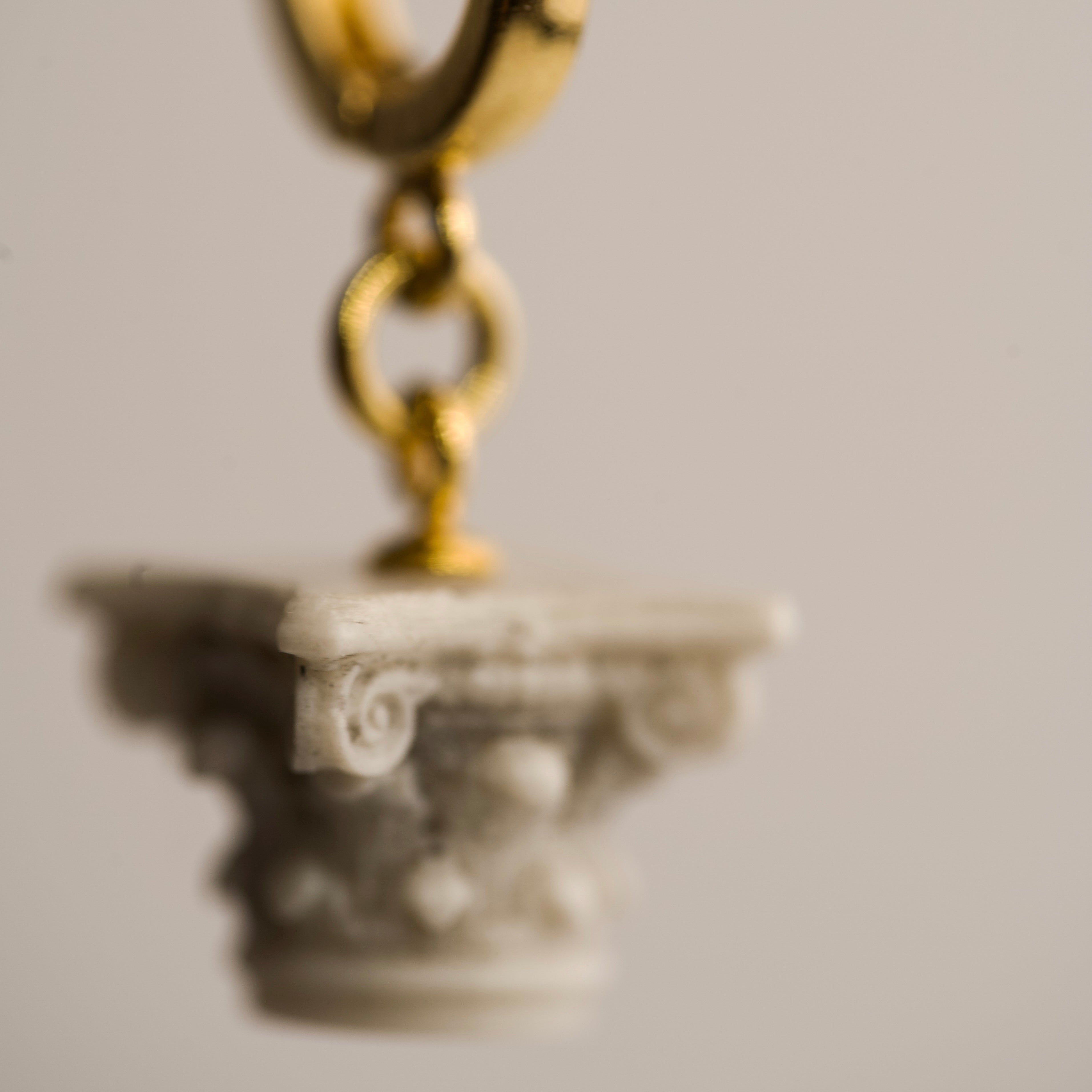 Corinth earring - decorative marble Corinth column charm on gold hoop against neutral background