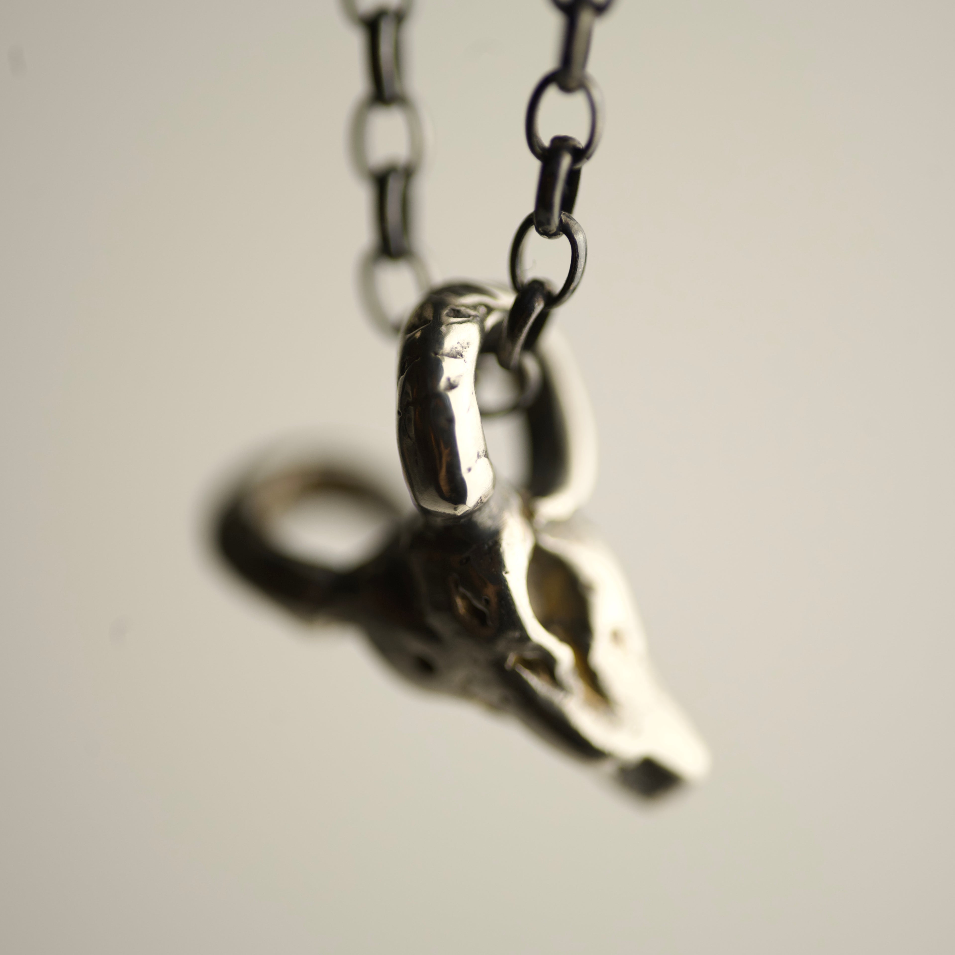 Ram Skull pendant on a chain against a neutral background - close-up of Greek mythology inspired charm