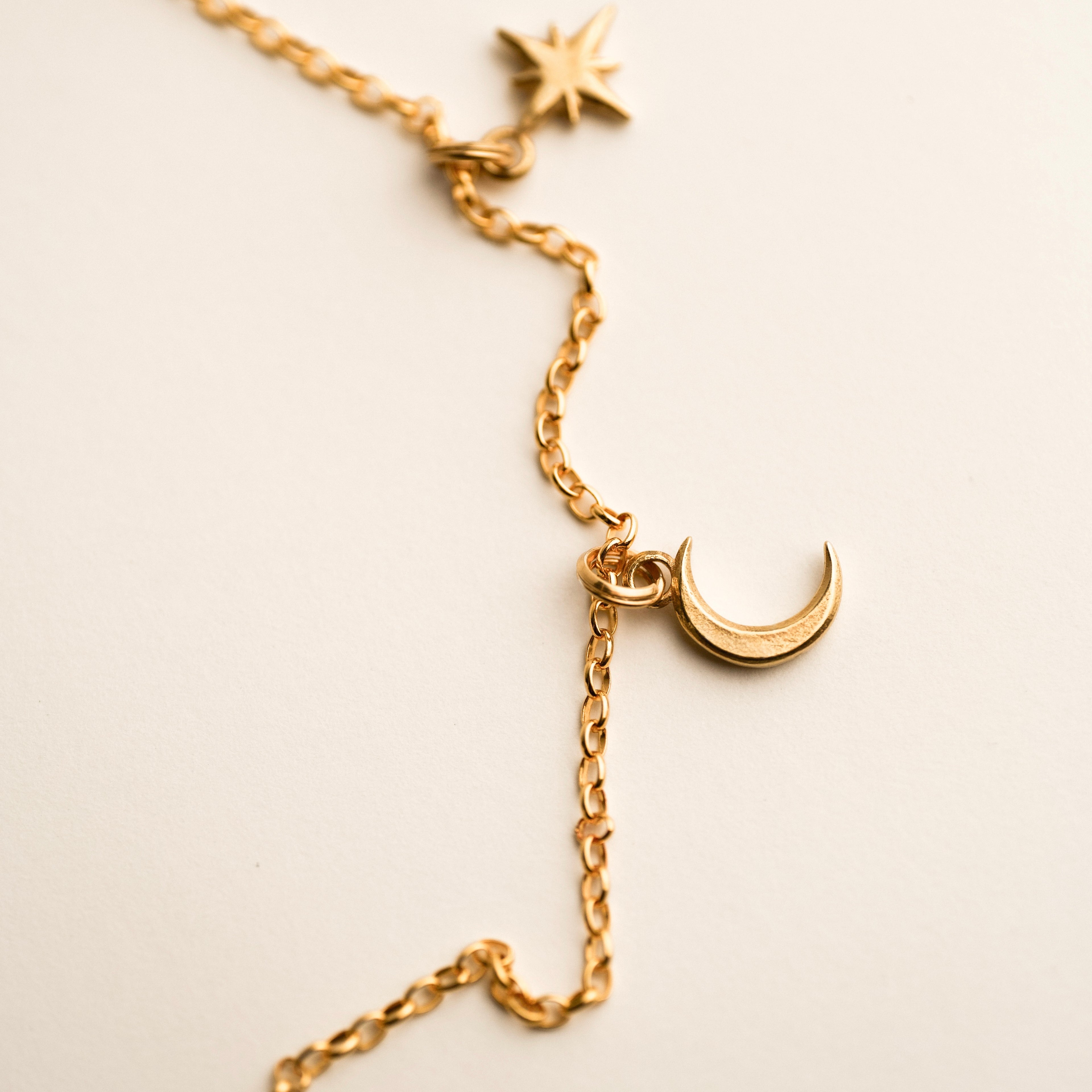 Asteria pendant - in gold variant - golden star and moon celestial necklace with gold chain on white surface