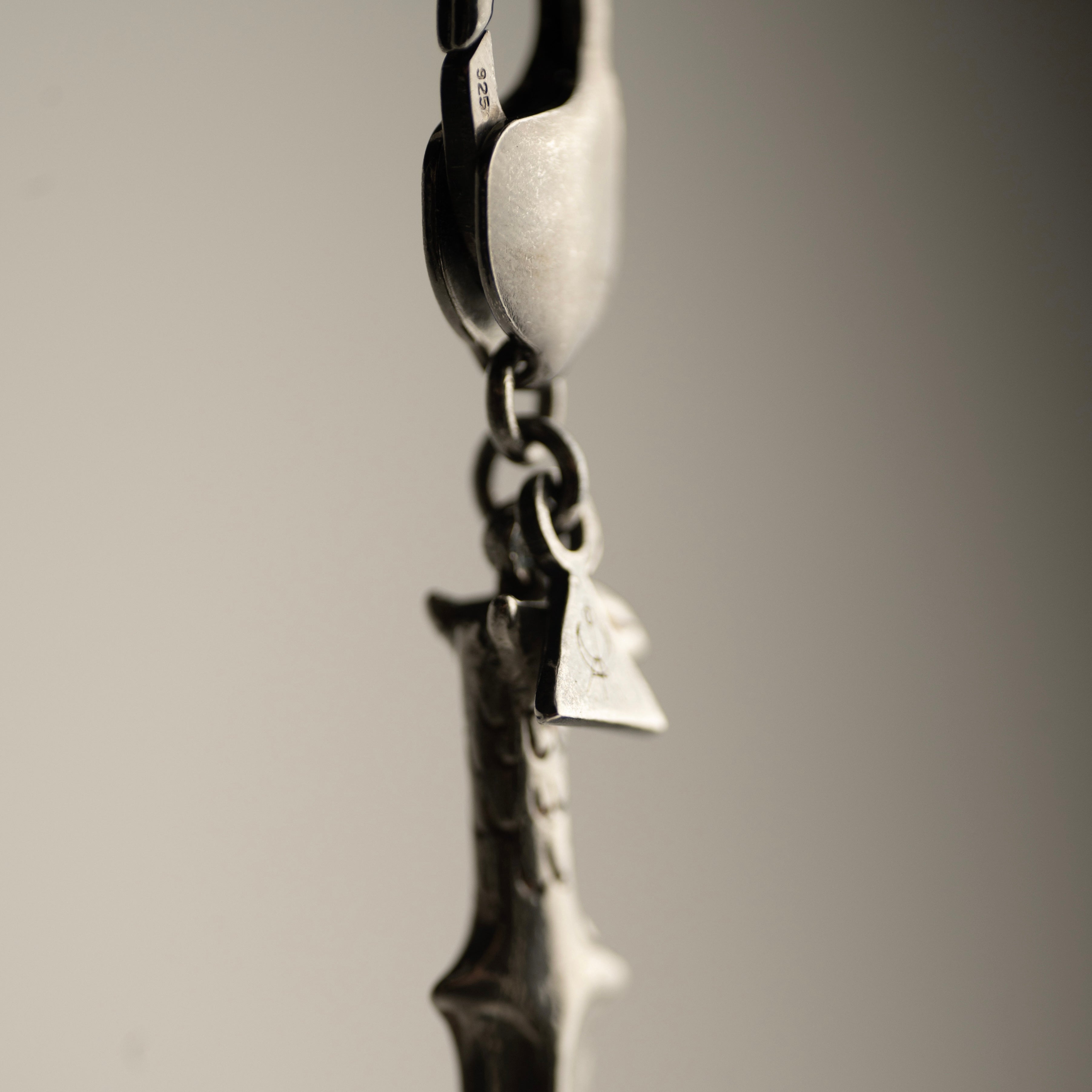 Close-up of lobster lock, fixture and logo detail of Griffin Sabre charm