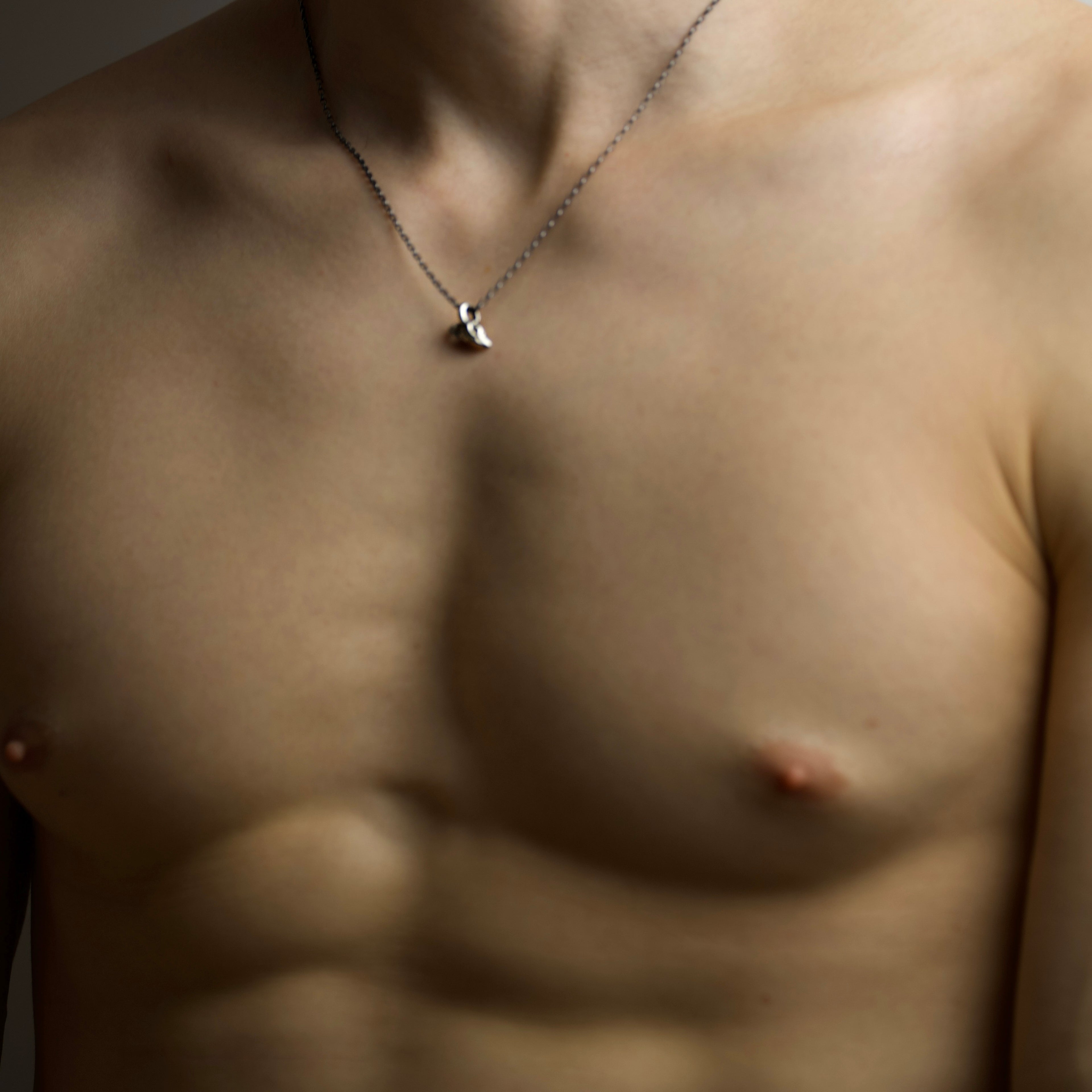 Close-up of a person wearing a Ram Skull pendant on a neutral background - astrology jewelry styling shot