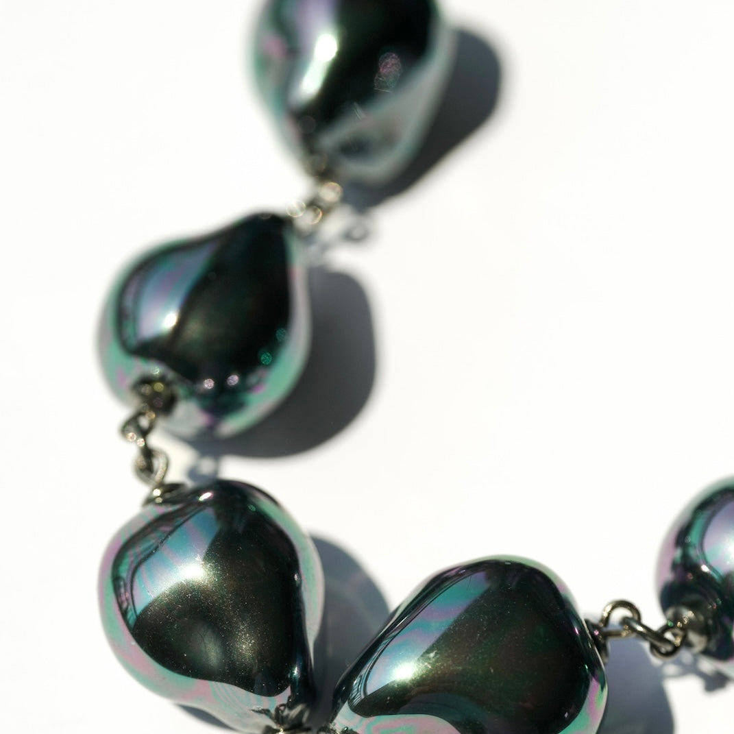 Close-up of a necklace with large, reflective beads on a white background