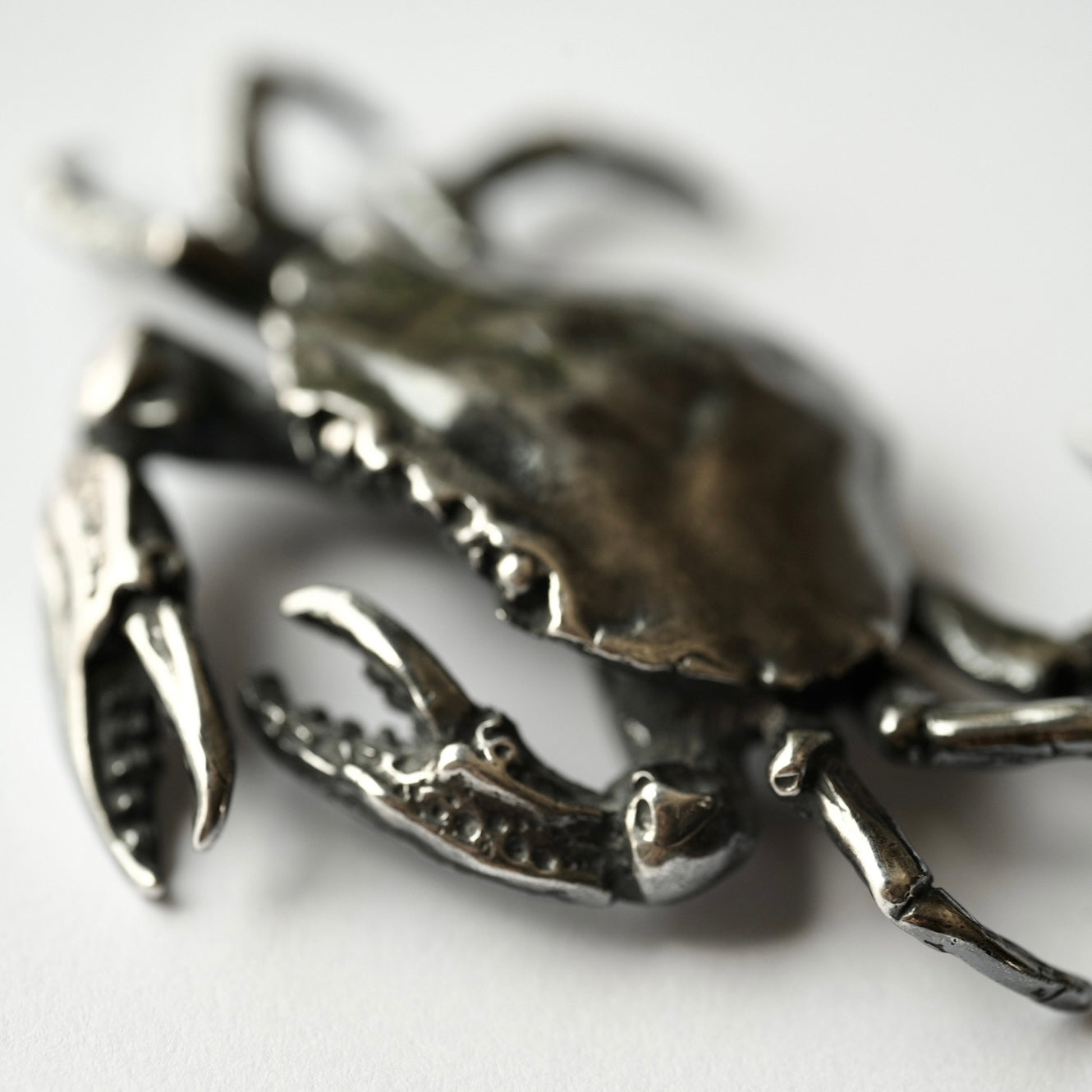 Silver crab brooch hand made by Macabre Gadgets on a white background - close up on natural ocean details of the crab