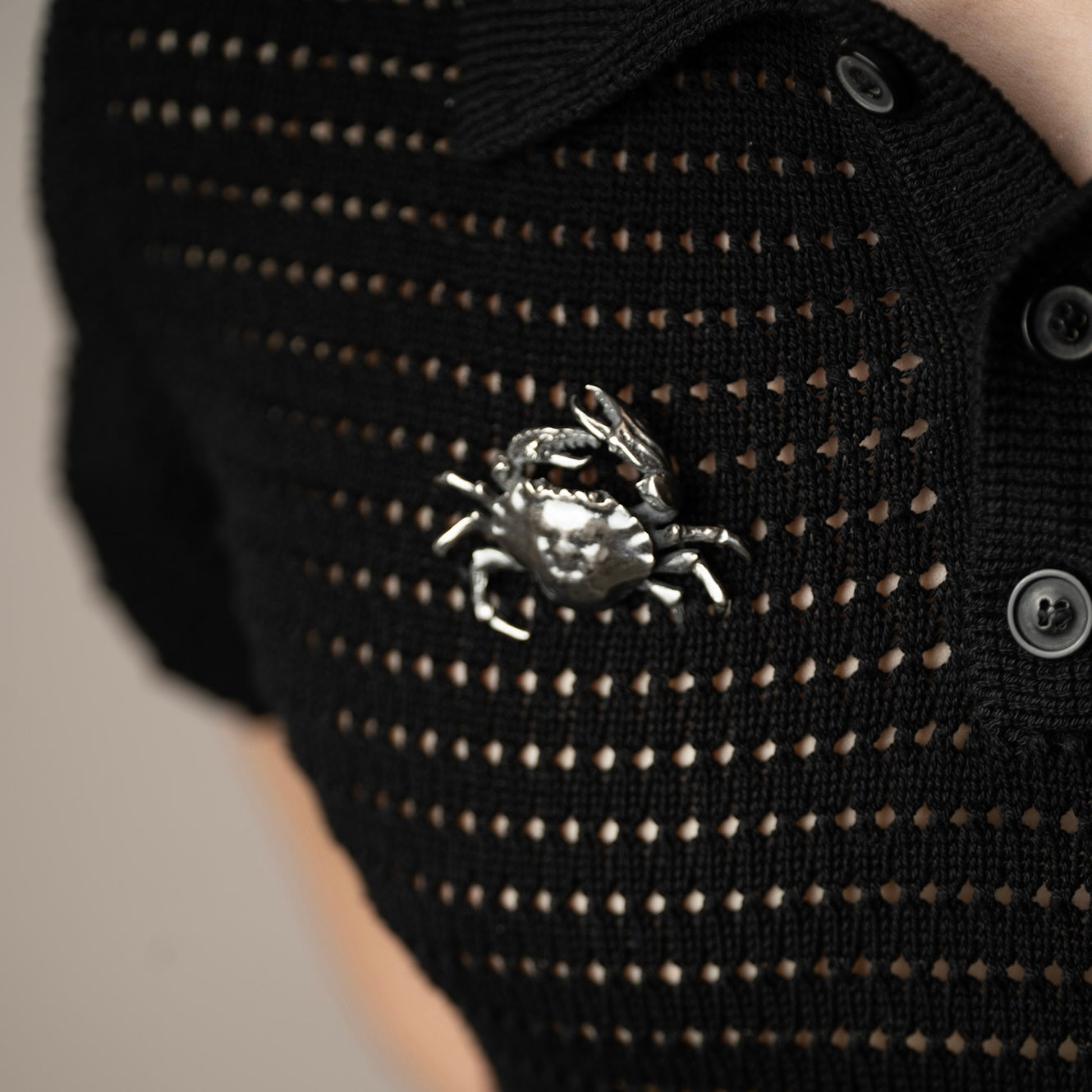 Black knit sweater with a silver crab brooch by Macabre Gadgets on a neutral background