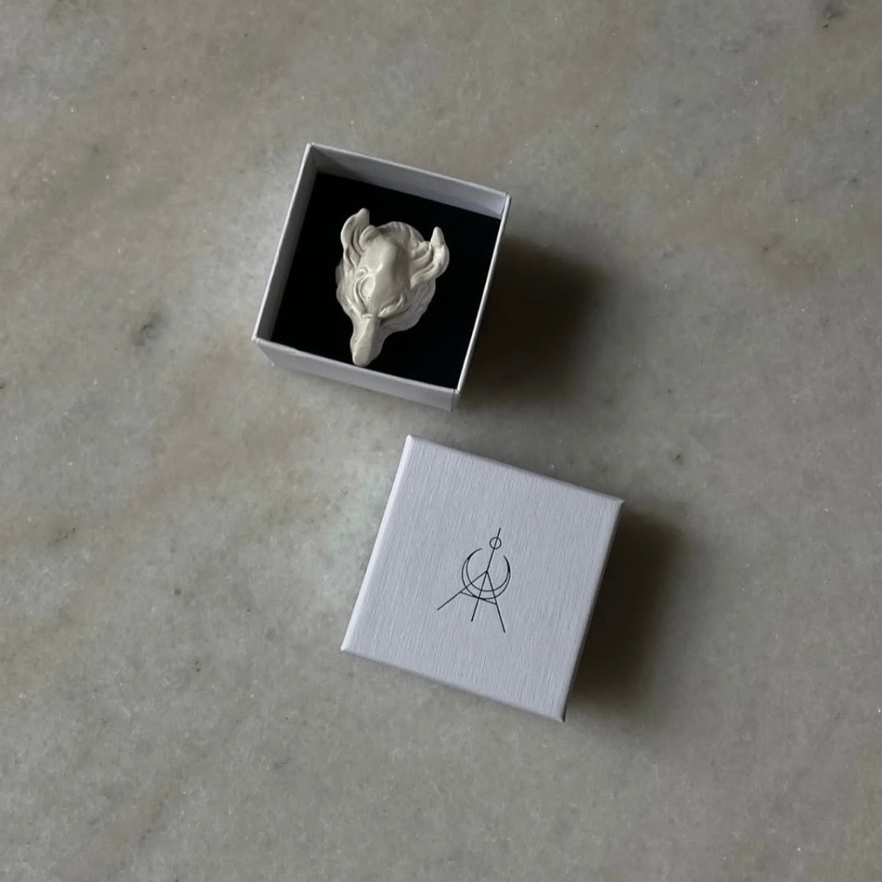 Wolf wing hand crafted in marble by Macabre Gadgets in a white minimalistic box on a white marble