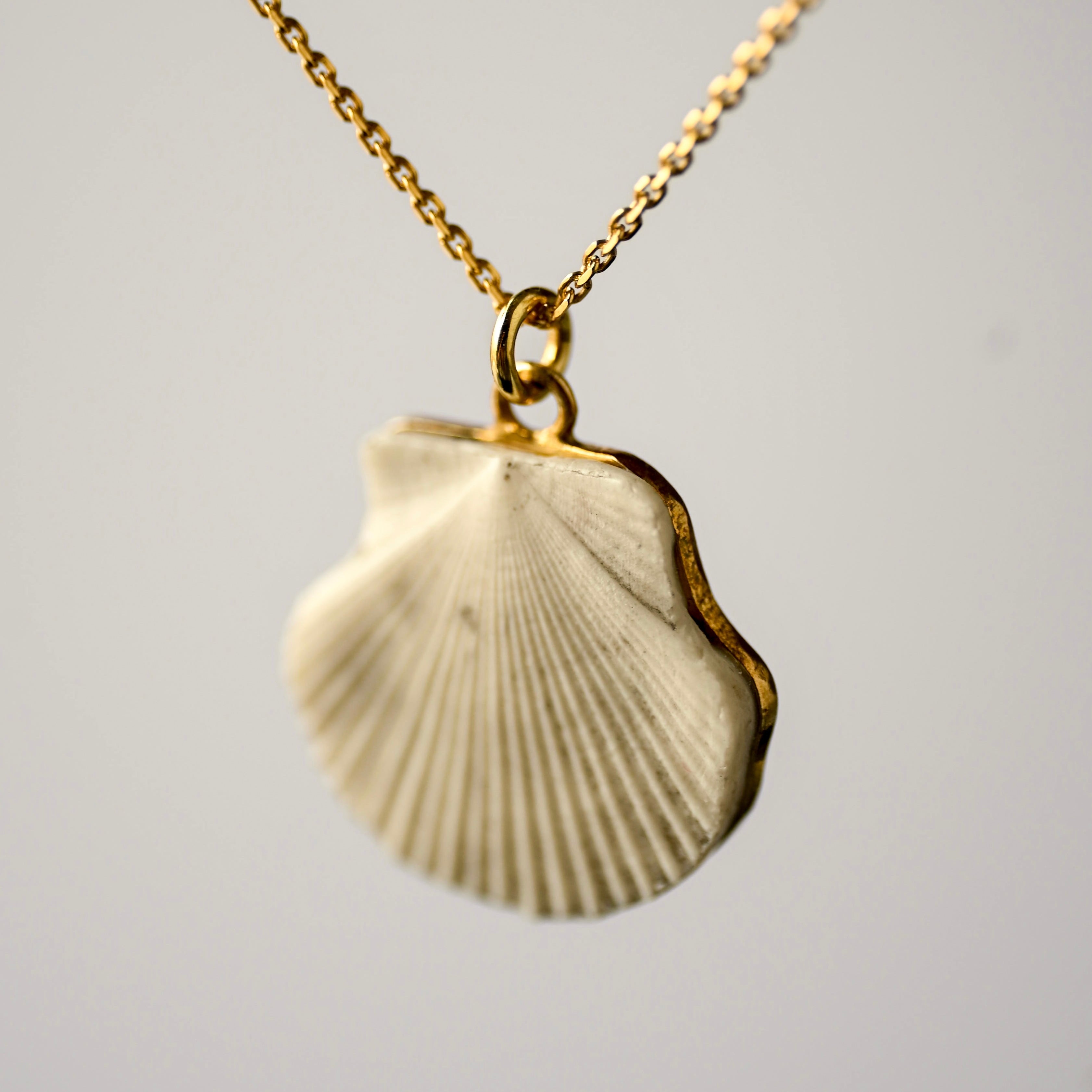 Sea shell pendant, 24K gold plated variant, on a light grey background - medium size pendant in the shape of a scallop shell fixed on gold plated sterling silver chain. 