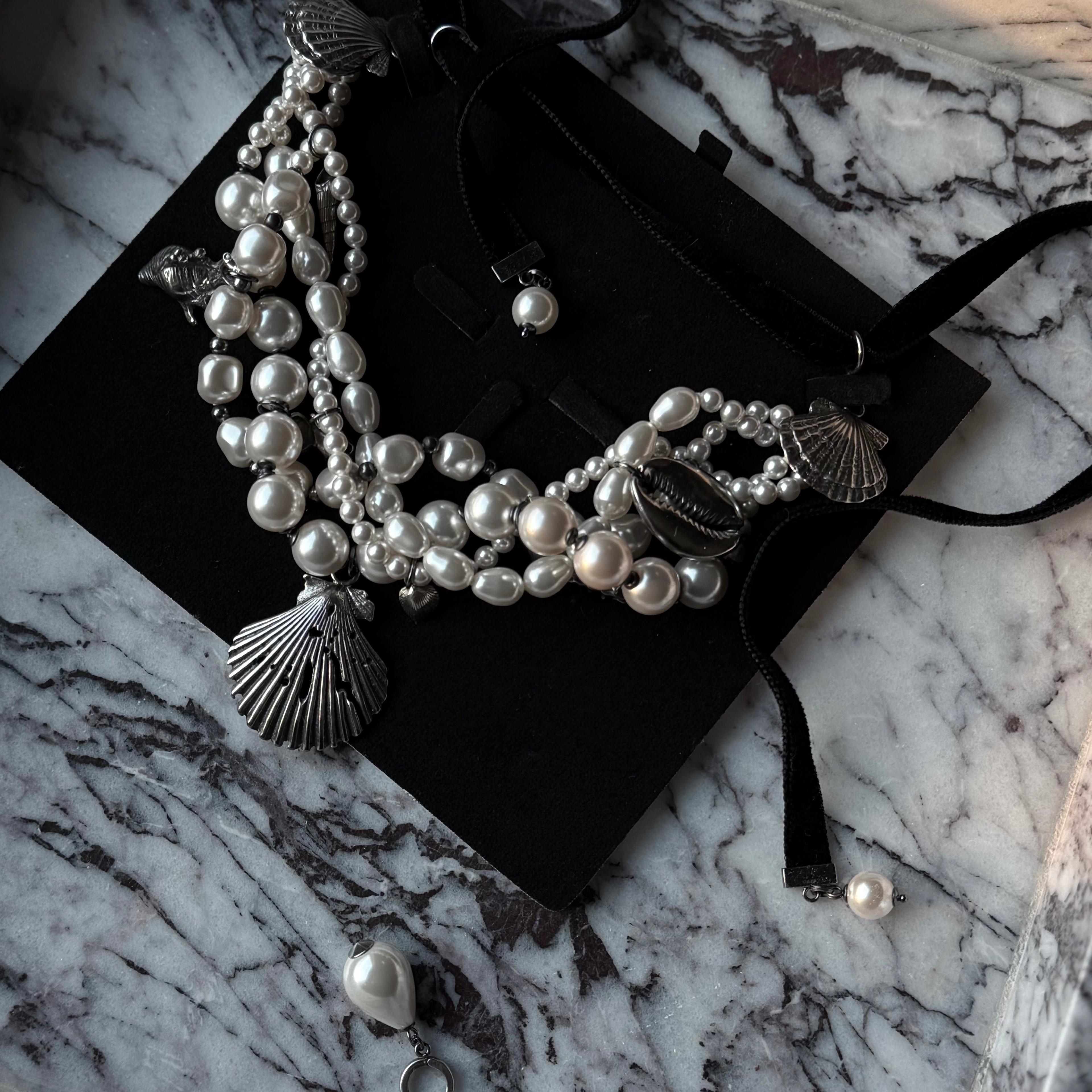 Siren necklaces by Macabre Gadgets: a massive hand crafted statement necklace made of glass pearls and sterling silver shells. In a black box on a white marble surface. The perfect siren core fashion accessory.
