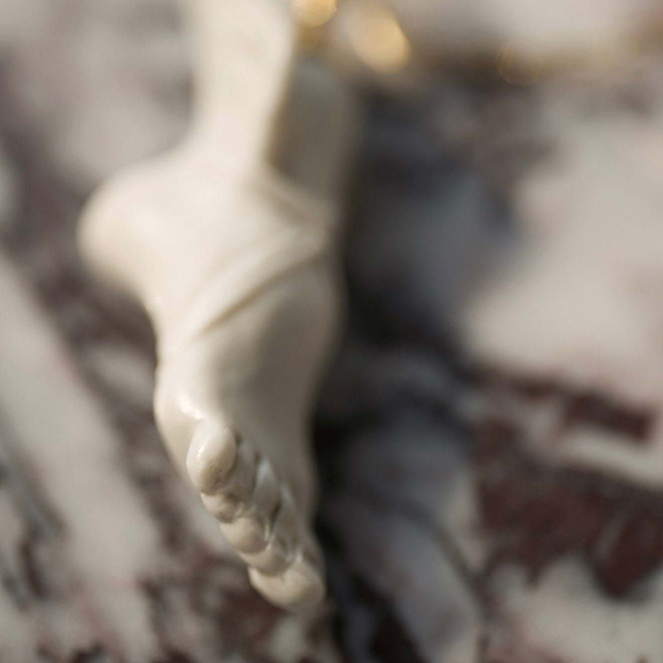 Macro close up on a white marble statue charm or pendant in a form of a Perseus foot with winged sandal of Hermes. Hand crafted by Macabre Gadgets and set on a 24k gold plated sterling silver 50cm anchor chain 