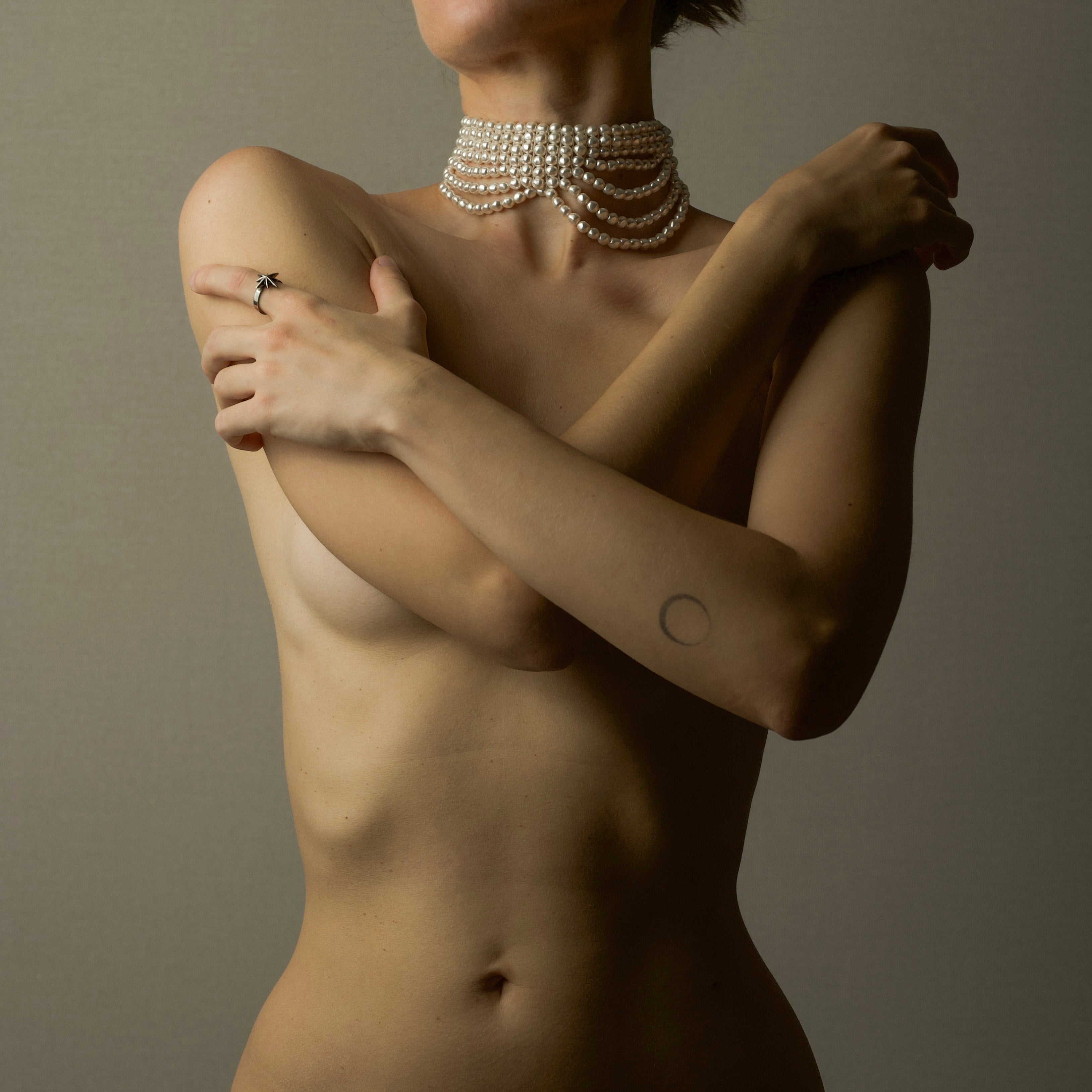 Model wearing multi strand pearl choker on a grey background replicating Ancient Greek sculpture of Venus