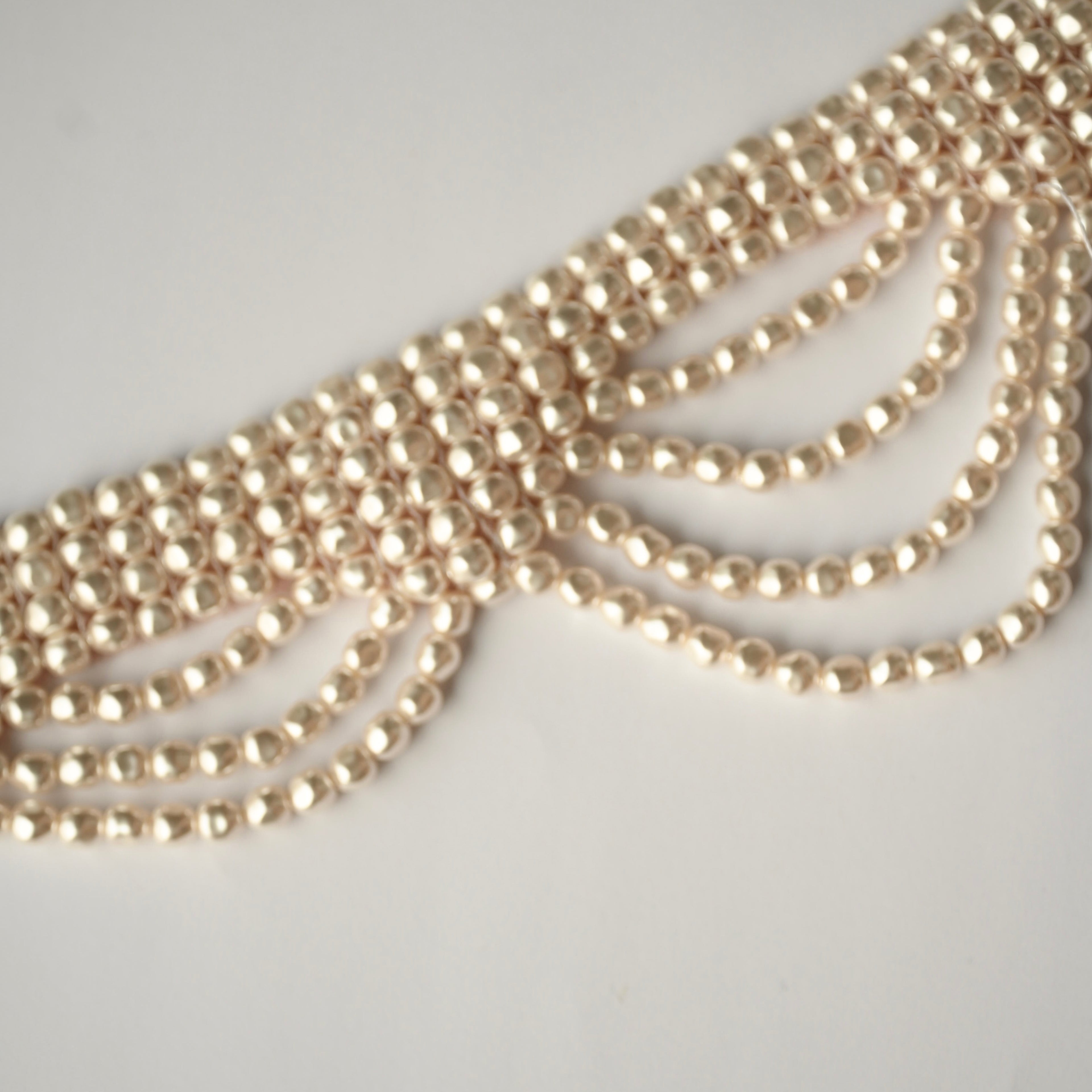 Close-up of a multi strands baroque pearl choker on a light grey background
