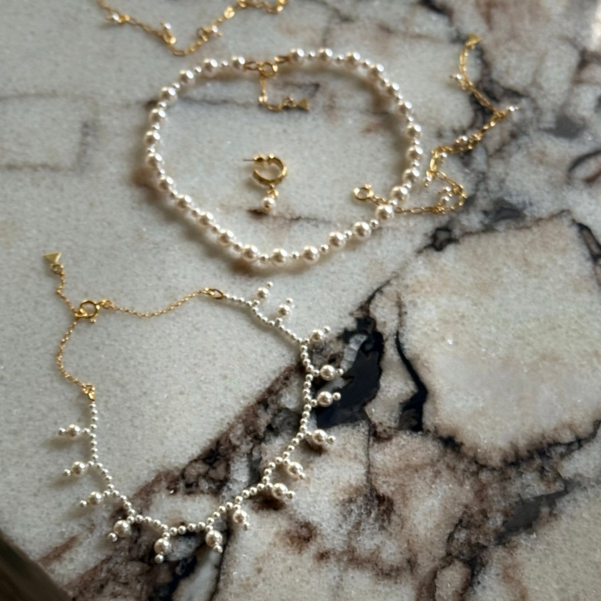 Aegean Pearl choker along with other pearl necklaces by Macabre Gadgets on a marble surface