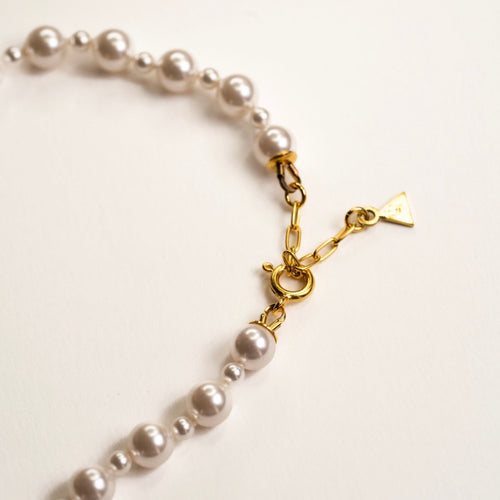Aegean Pearl choker close up on a lobster clasp and a small brand logo detail at the end of the necklace