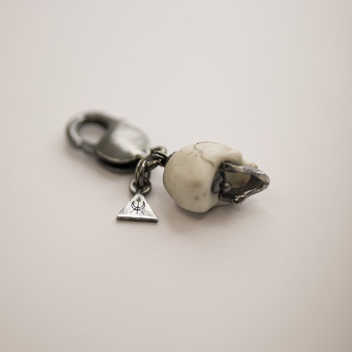 Marble skull charm — back view of white marble skull showing sterling silver logo detail on white surface