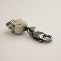 Marble skull charm — white marble with sterling silver jaw lying on white surface, lobster clasp in focus