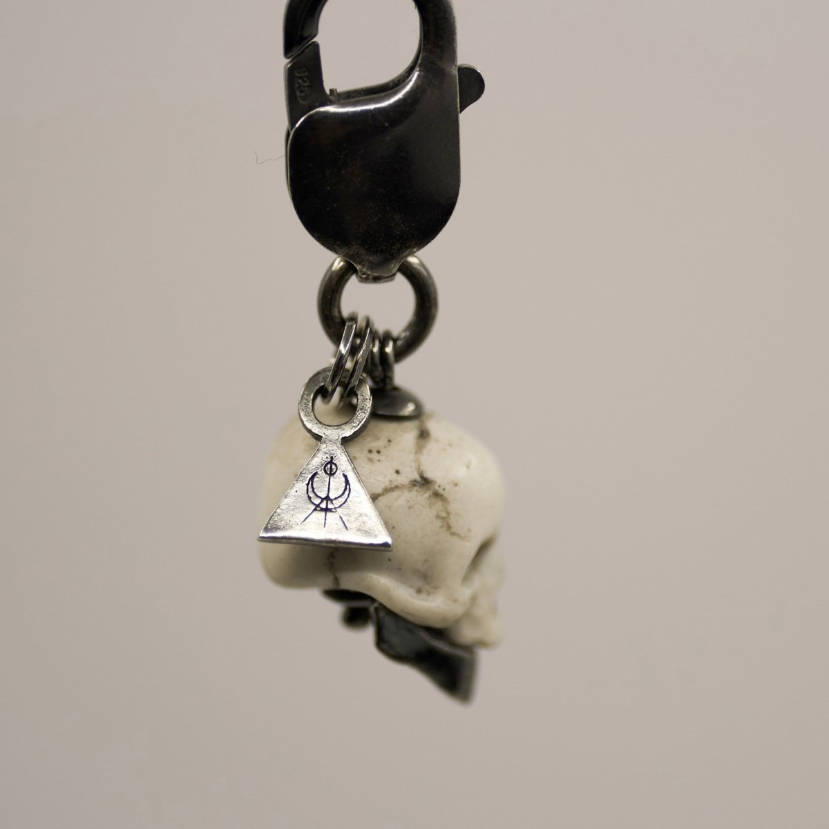 Marble skull charm — white marble skull with sterling silver jaw, logo charm and lobster lock visible, general view