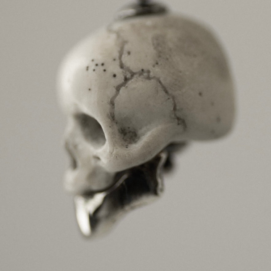 Marble skull charm close-up — white marble skull with sterling silver jaw, bone texture and carving detail