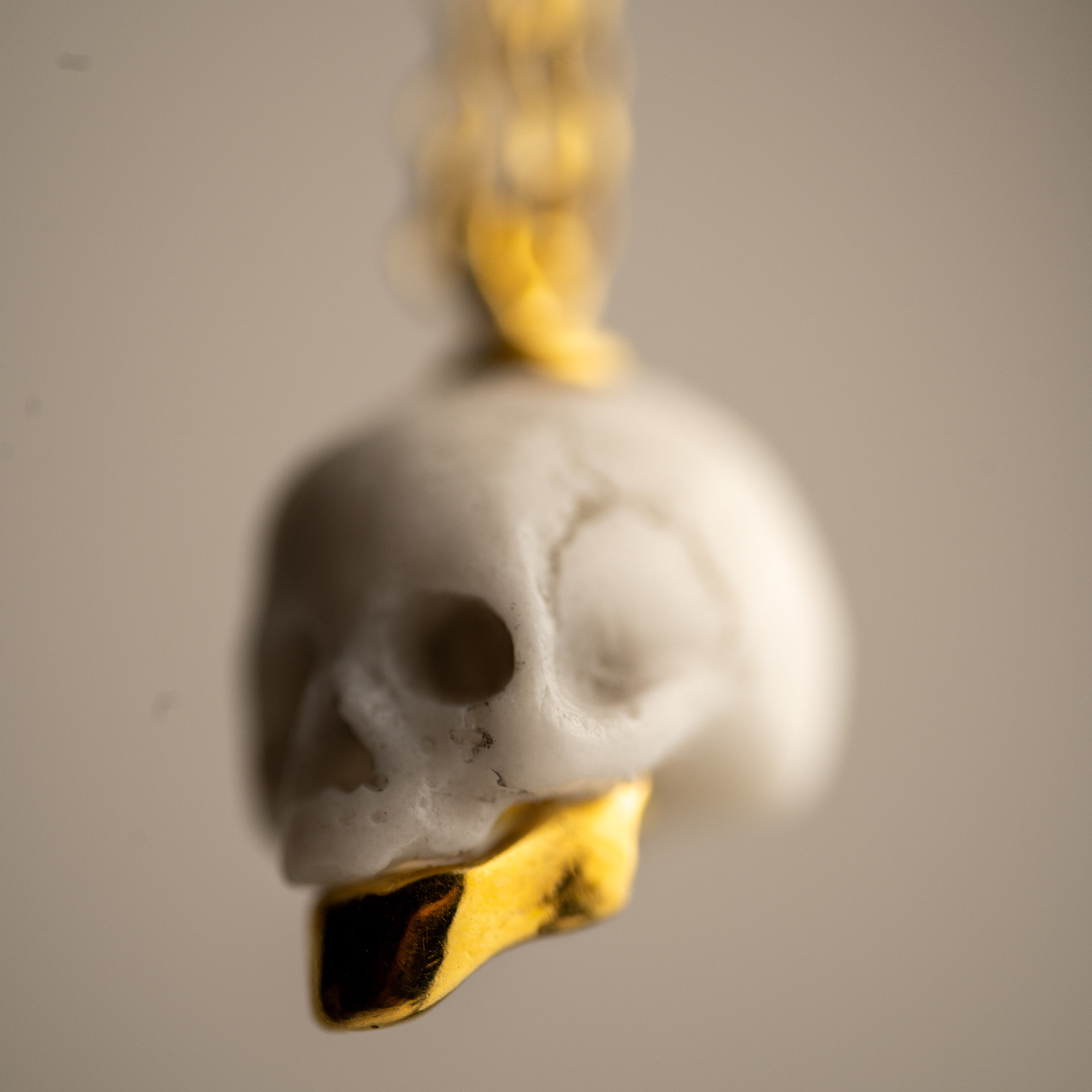 Miniature marble skull pendant with gold-plated sterling silver jaw on chain — white marble, neutral background