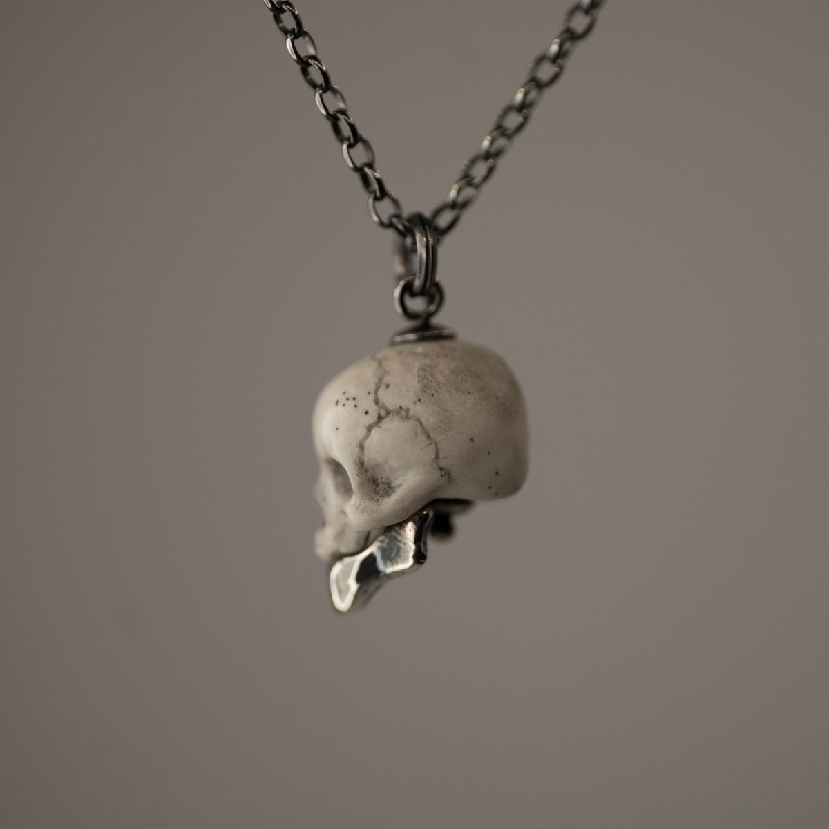Miniature marble skull pendant with sterling silver jaw — white marble, profile view showing chain fixture