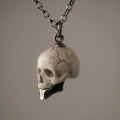 Miniature marble skull pendant with sterling silver jaw — white marble, semi-profile view showing chain fixture