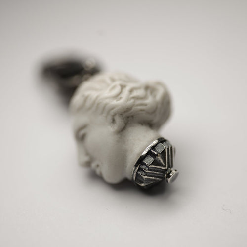 Marble mini charm in shape of woman head on white surface