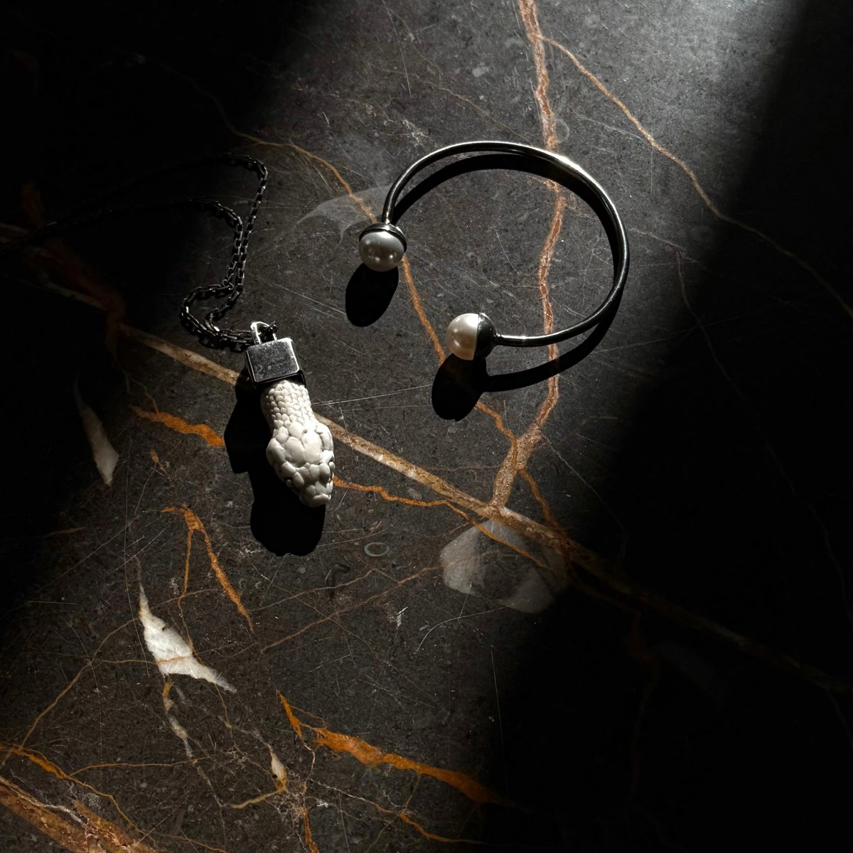 Aspis pendant with a bracelet on a dark marble surface