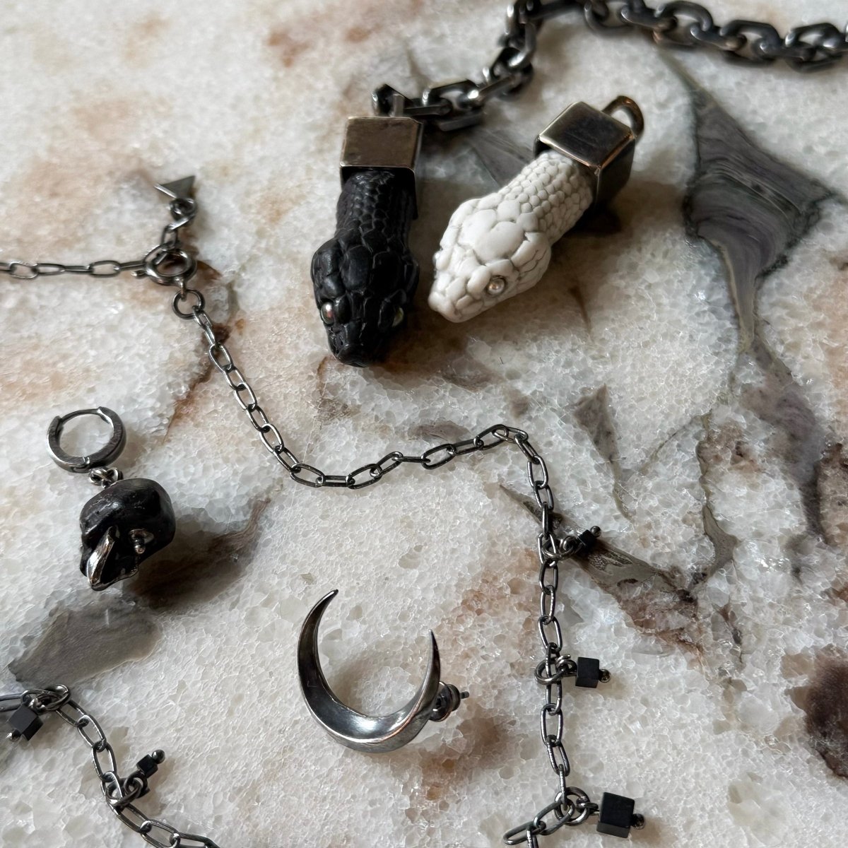 Aspis pendant white and black variants together on a marble surface