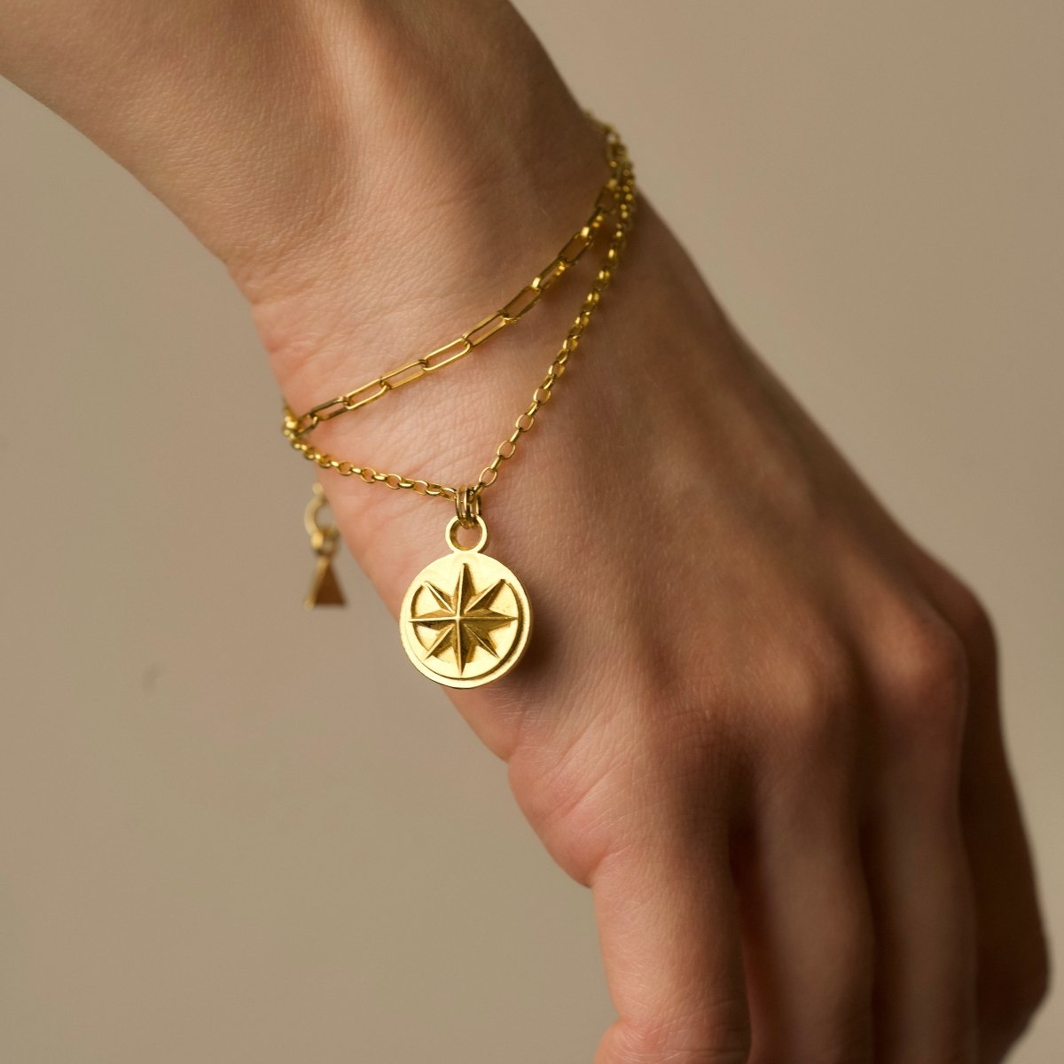 Aster bracelet on a model's hand, focus on coin charm with moon and star symbols