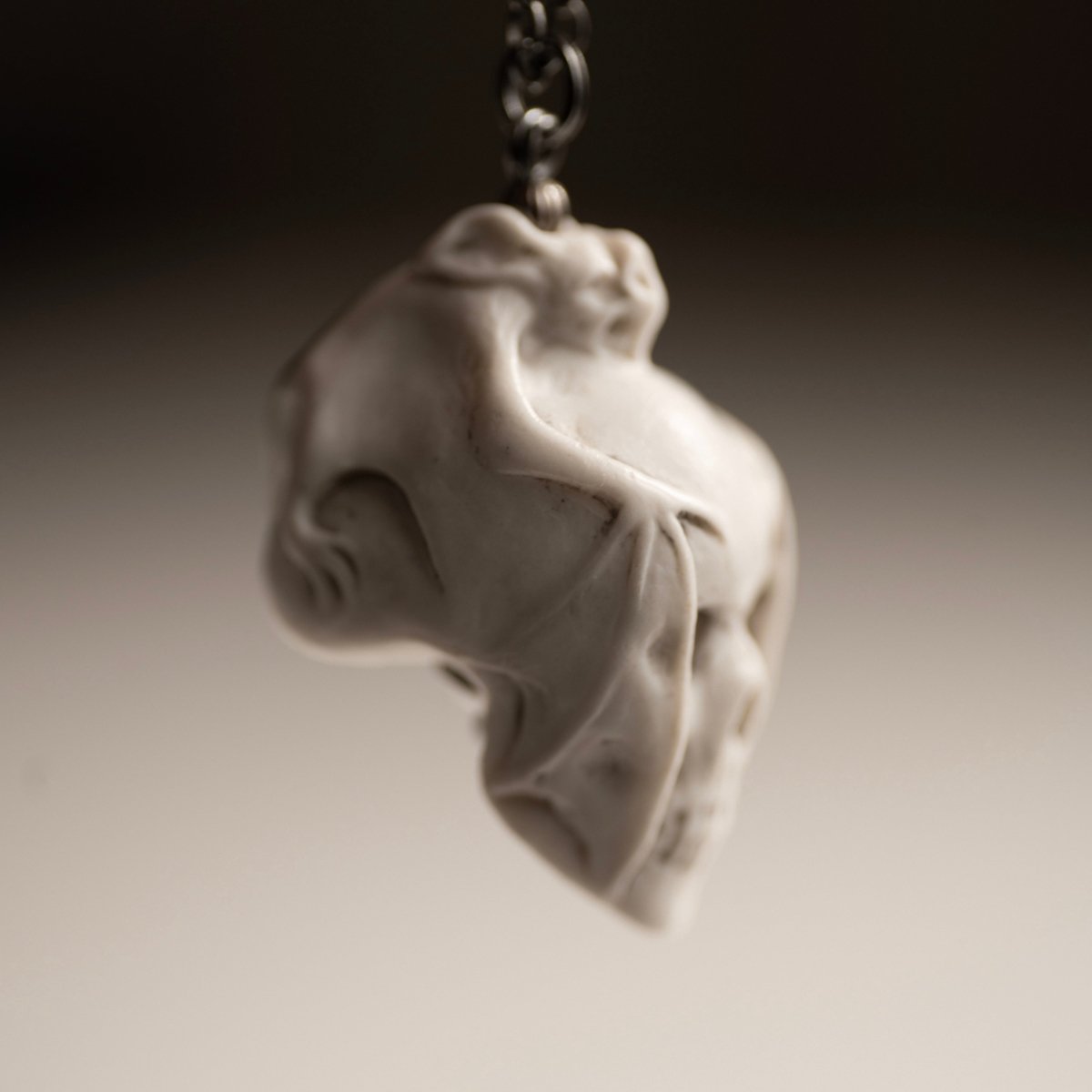 Skull & Bat pendant - white variant - focus on the bat's wing covering the skull's face
