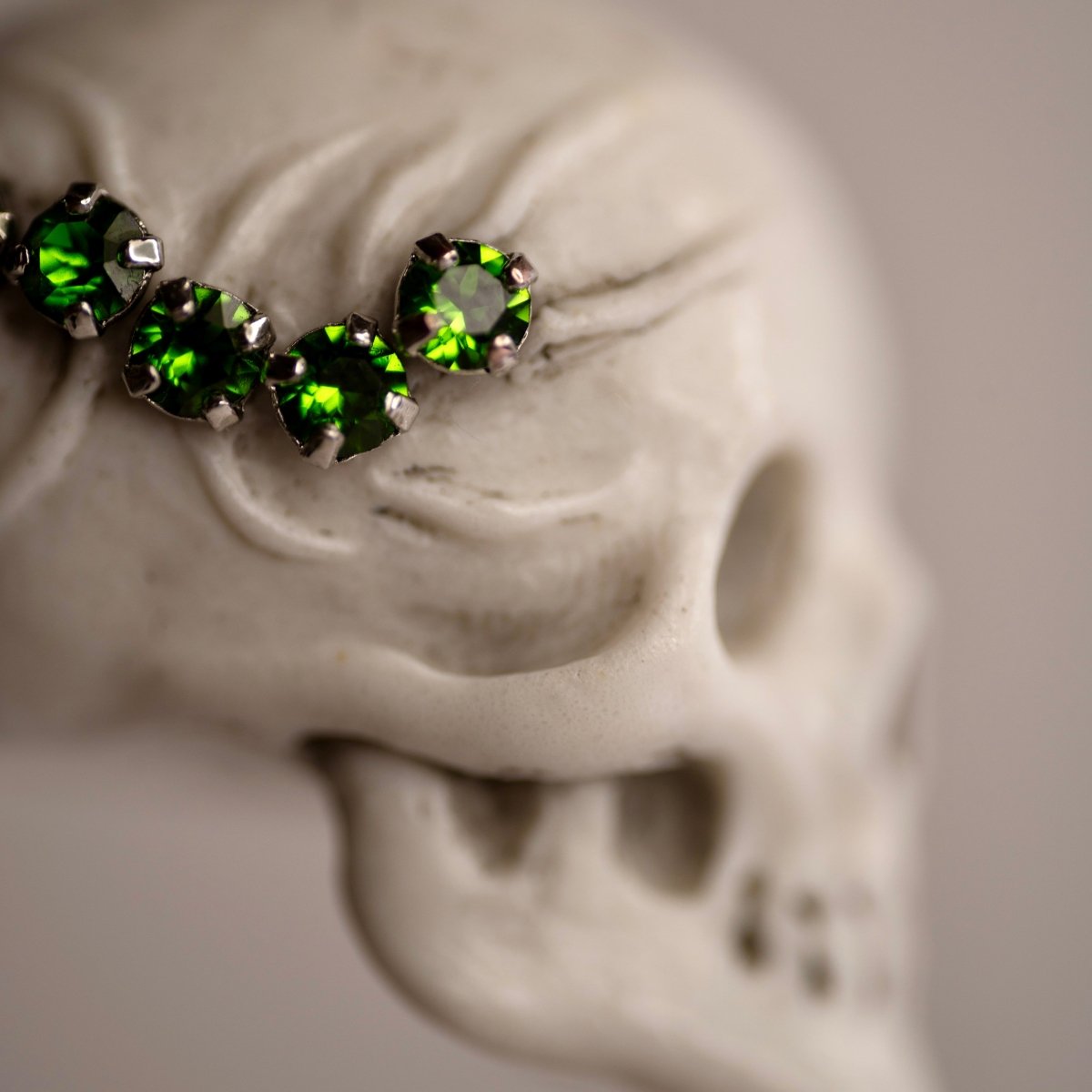 Beetles Skull pendant — white marble variant — close up of green glass gemstones set into the marble skull surface
