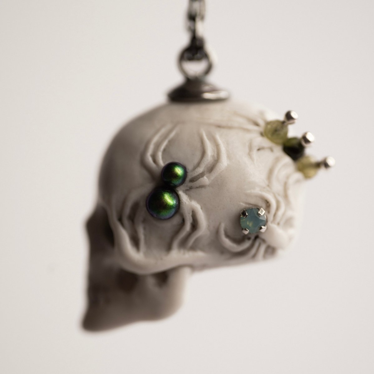 Beetles Skull pendant — white marble variant — side view showing black glass pearl spider set into the marble surface