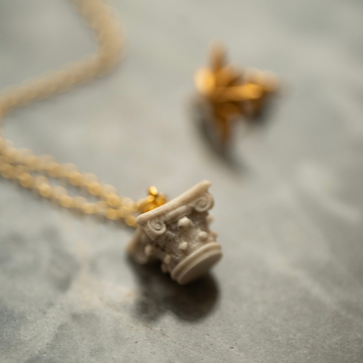 Corinth pendant lying on a dark stone surface