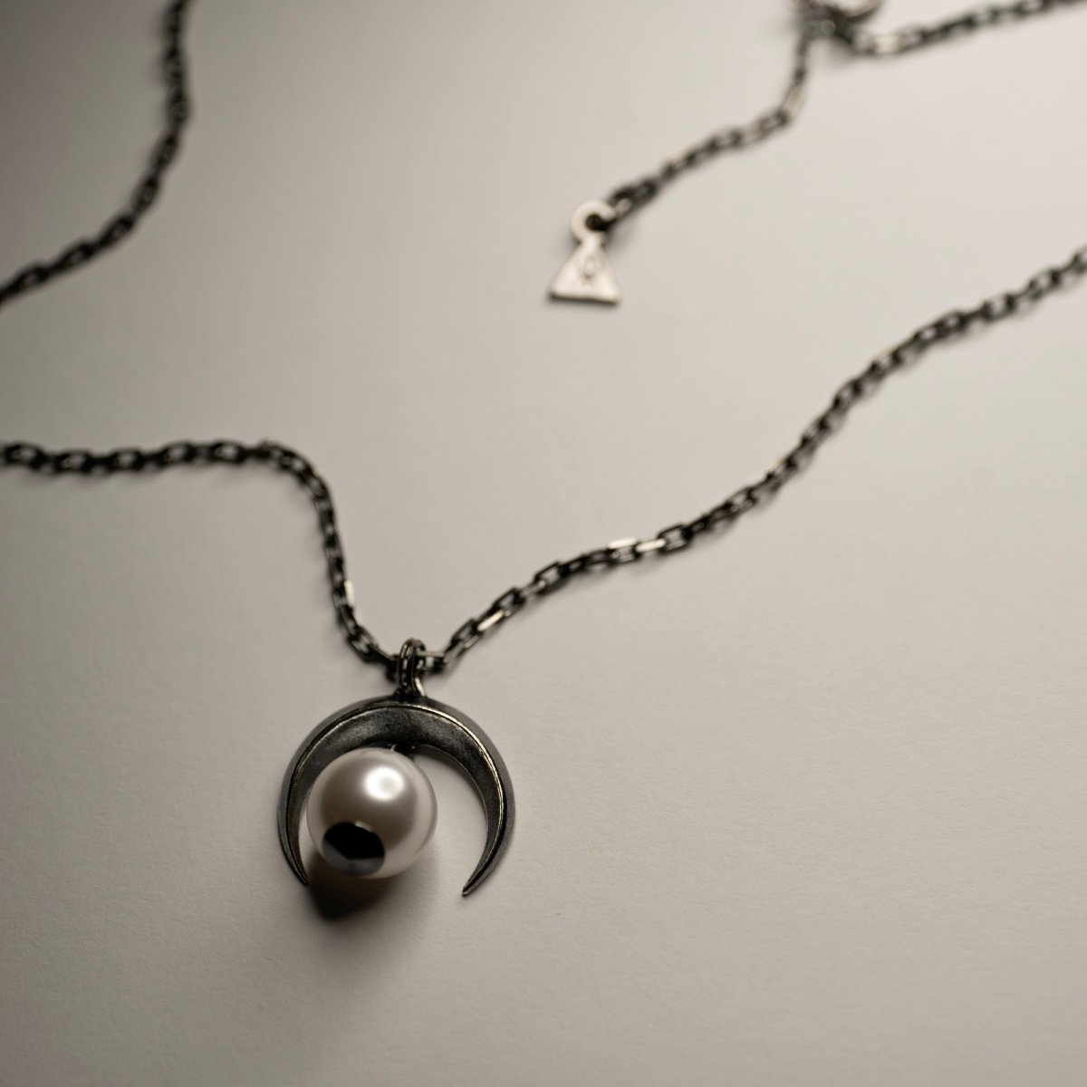 Crescent Moon Pendant silver variant on beige surface — oxidised sterling silver moon necklace