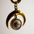 Crescent Oracle earring close-up showing gold-plated crescent moon and marble eye details, gothic astrology jewelry