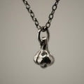 Garlic pendant - close-up of silver charm on silver chain necklace against neutral background