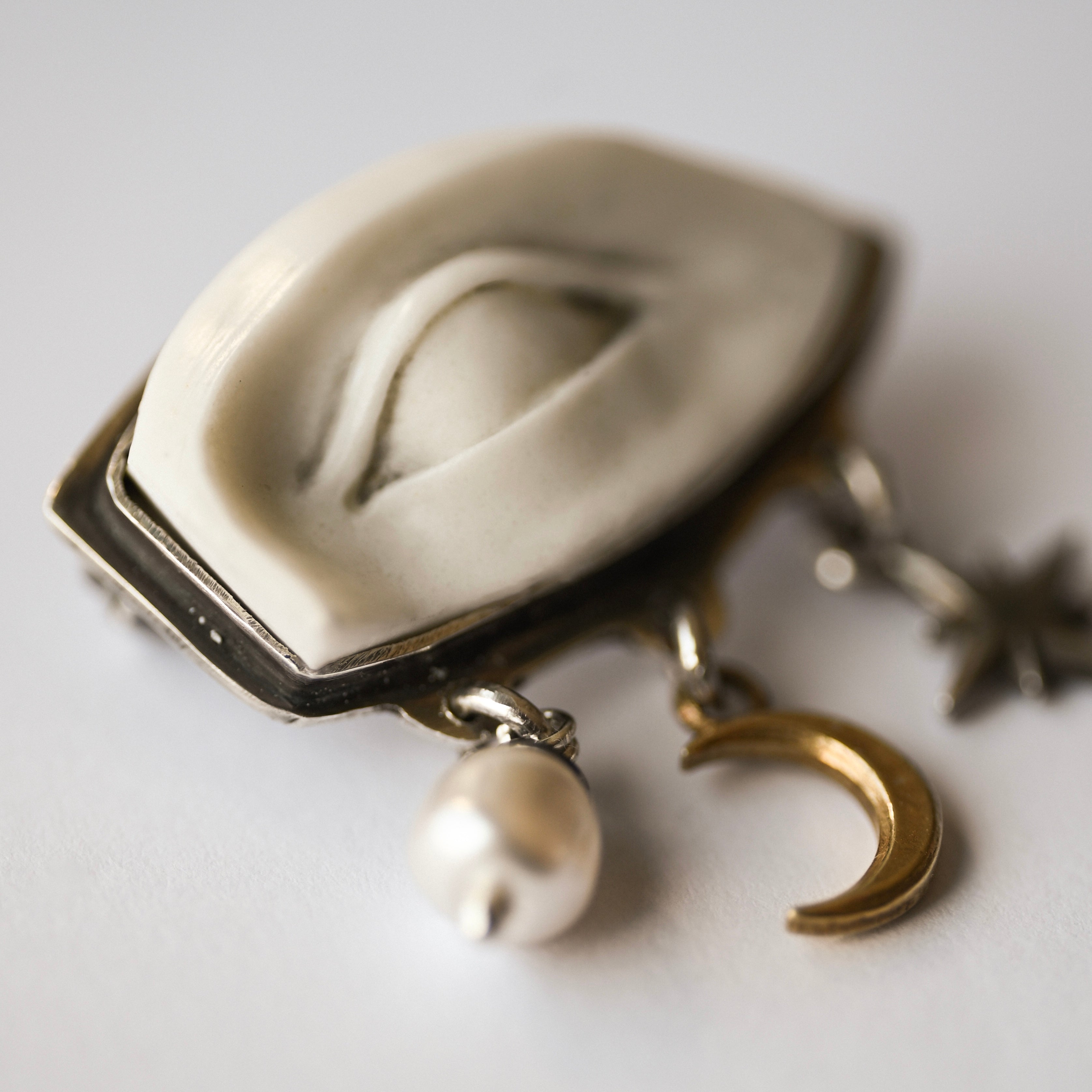 Close up on detailed white marble eye of an ancient Roman statue - a brooch by Macabre Gadgets with celestial pendants